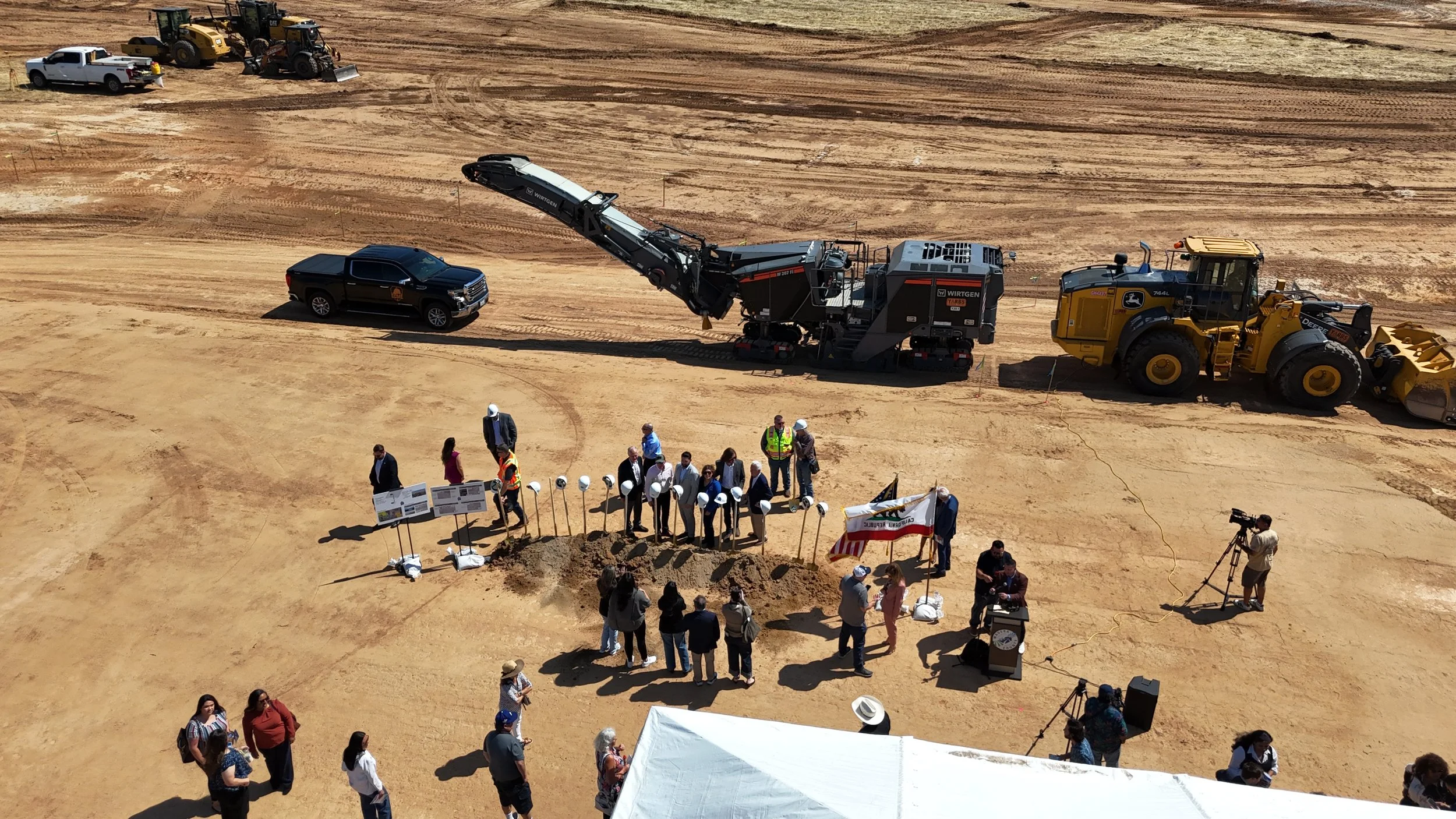 Groundbreaking participants taking a picture in front of the golden shovels and helmets.
