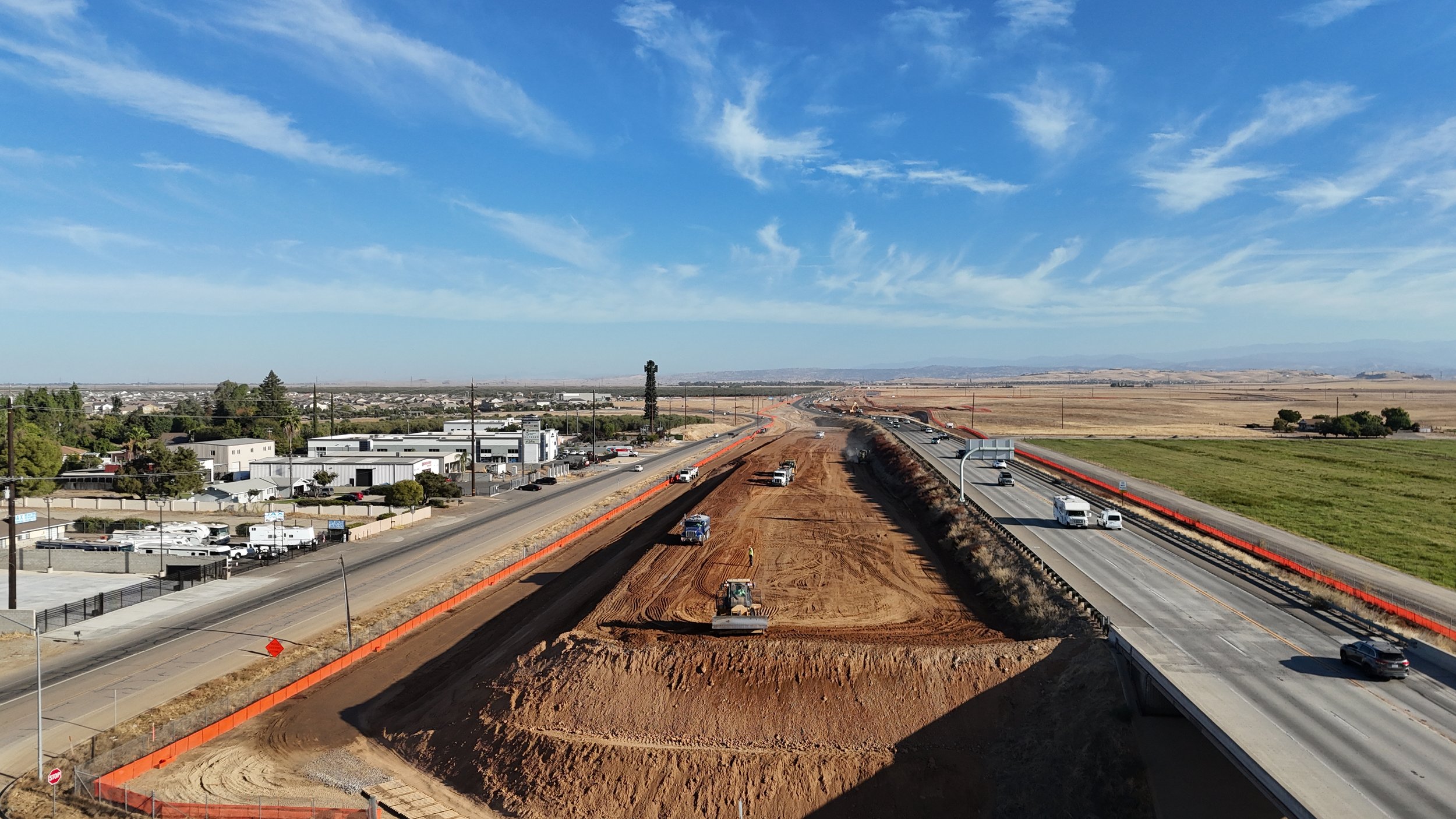 A direct side view of machinery compacting the soil left of the Avenue 11 bridge.