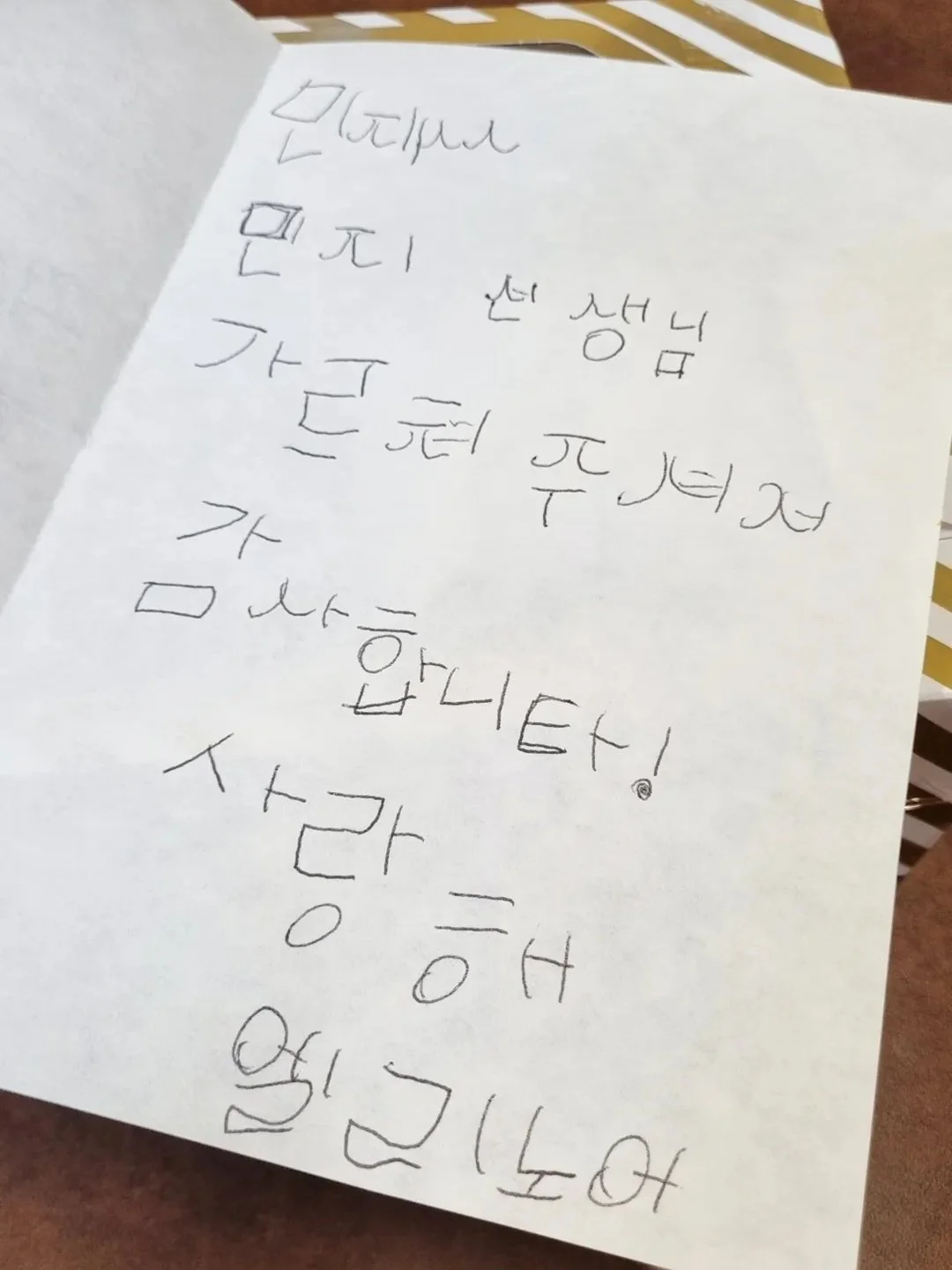 Handwritten note in Korean on a white sheet of paper.