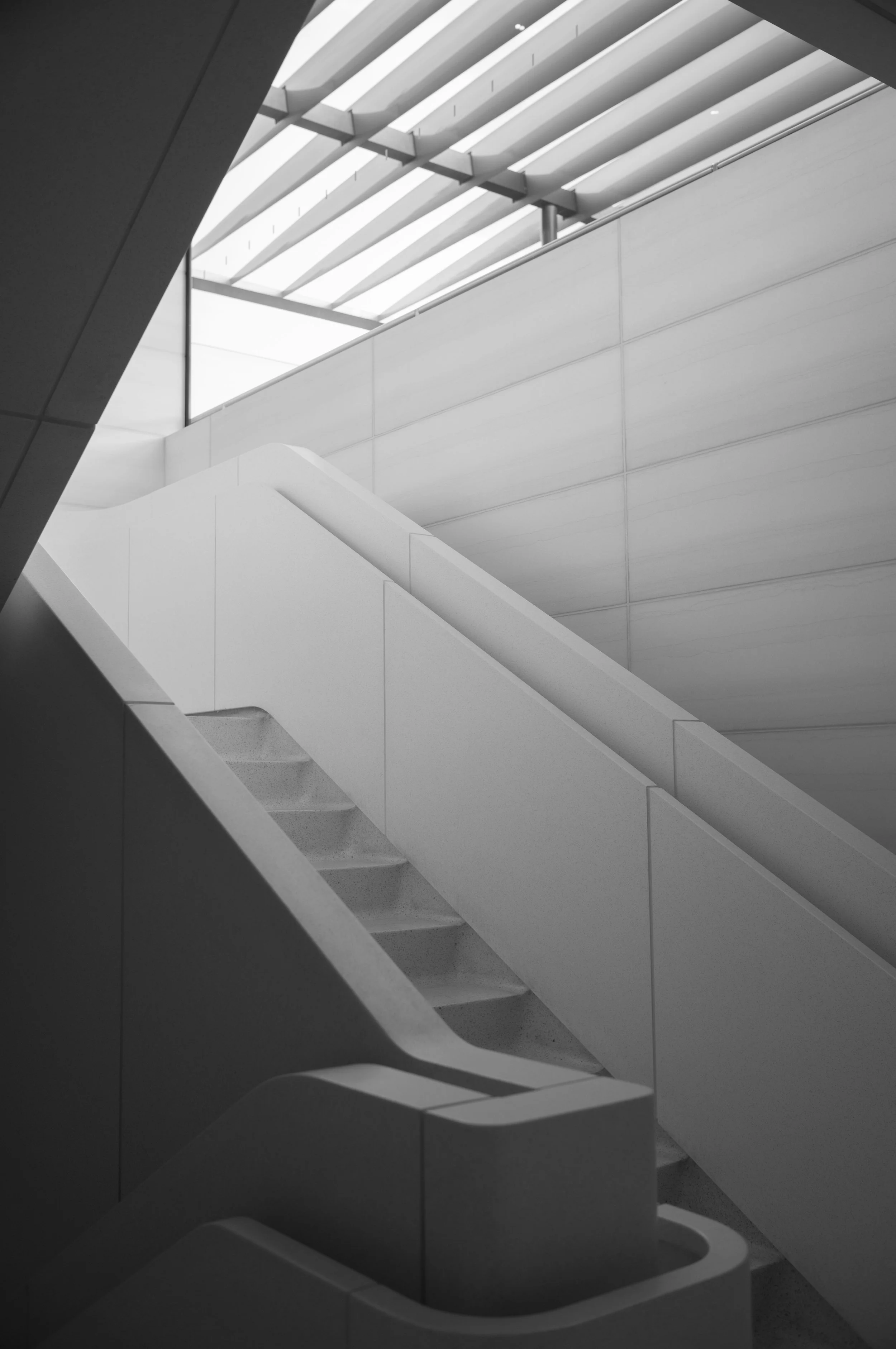Black and white photo of modern interior staircase with clean lines, enclosed by walls and a glass ceiling. Leica M Camera.  Film photography