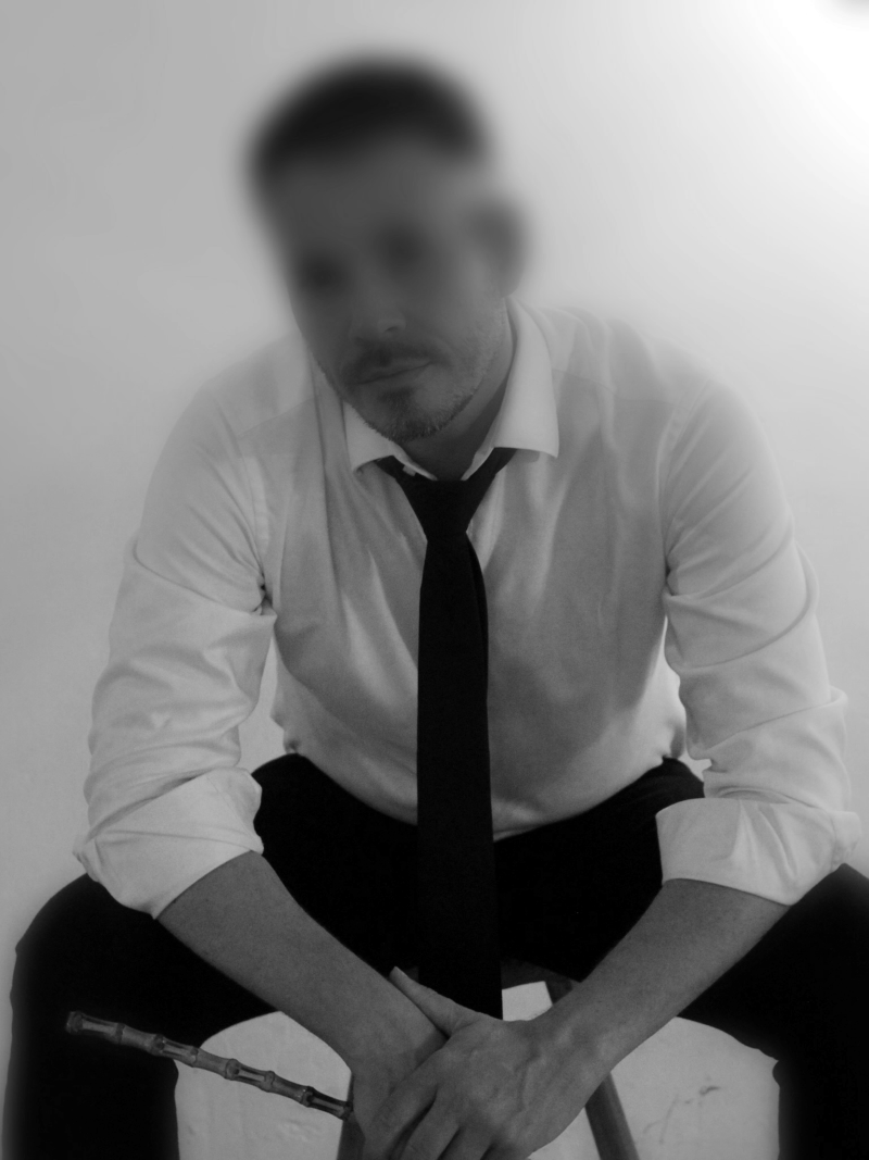 BDSM Gigolo, foto van een zittende man met een overhemd en zwarte stropdas