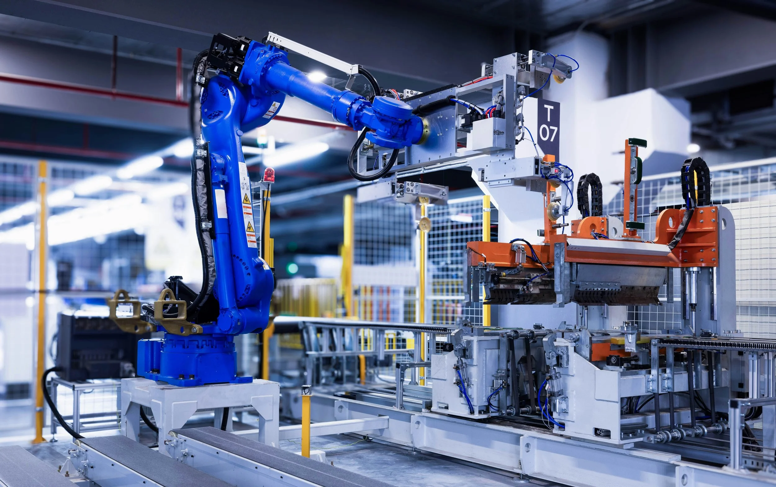 A blue robotic arm working on an industrial manufacturing process in a factory setting.