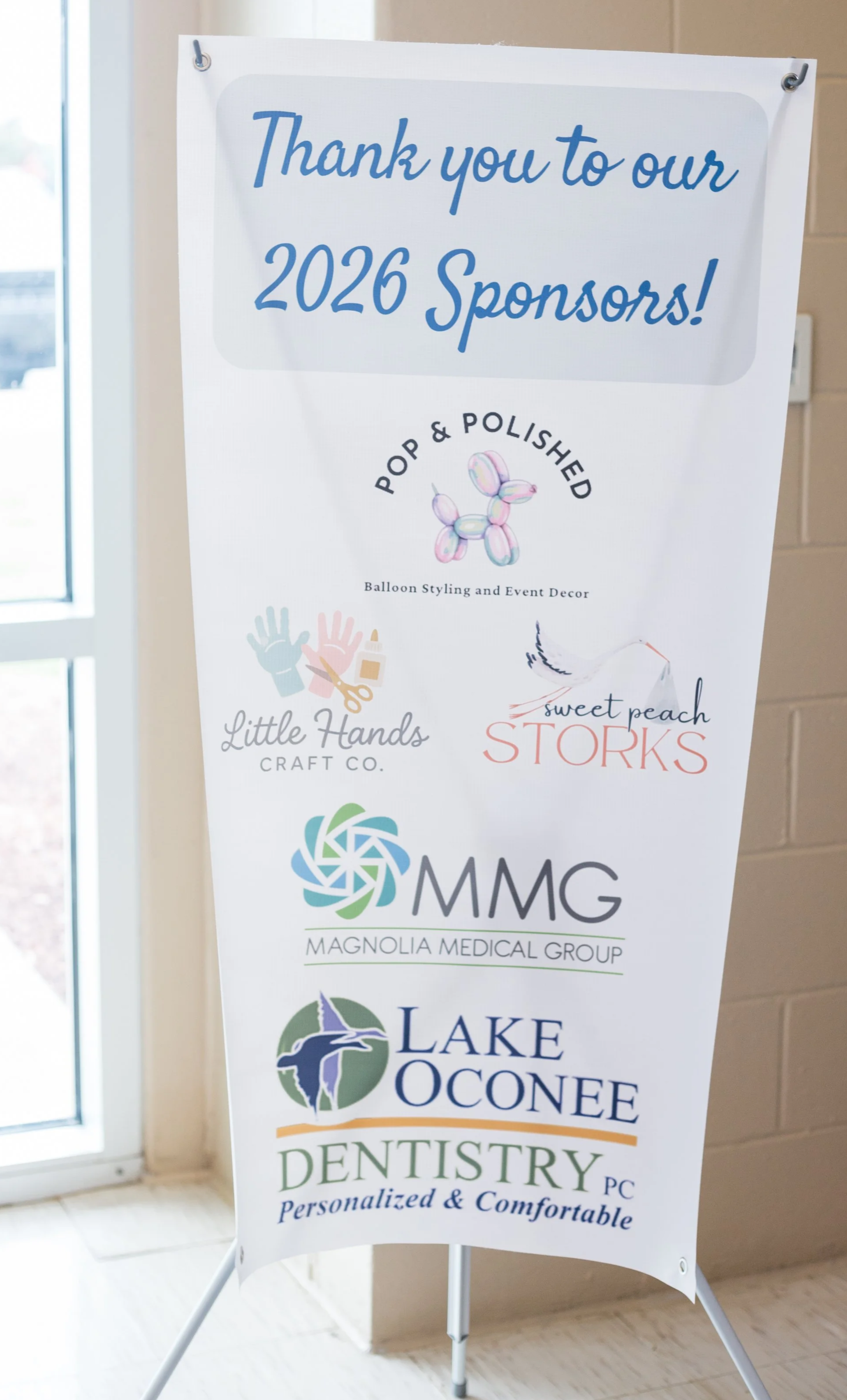 Banner thanking 2026 sponsors featuring logos for Pop & Polished, Little Hands Craft Co., Magnolia Medical Group, Lake Oconee Dentistry. Icon of a balloon dog and a stork.