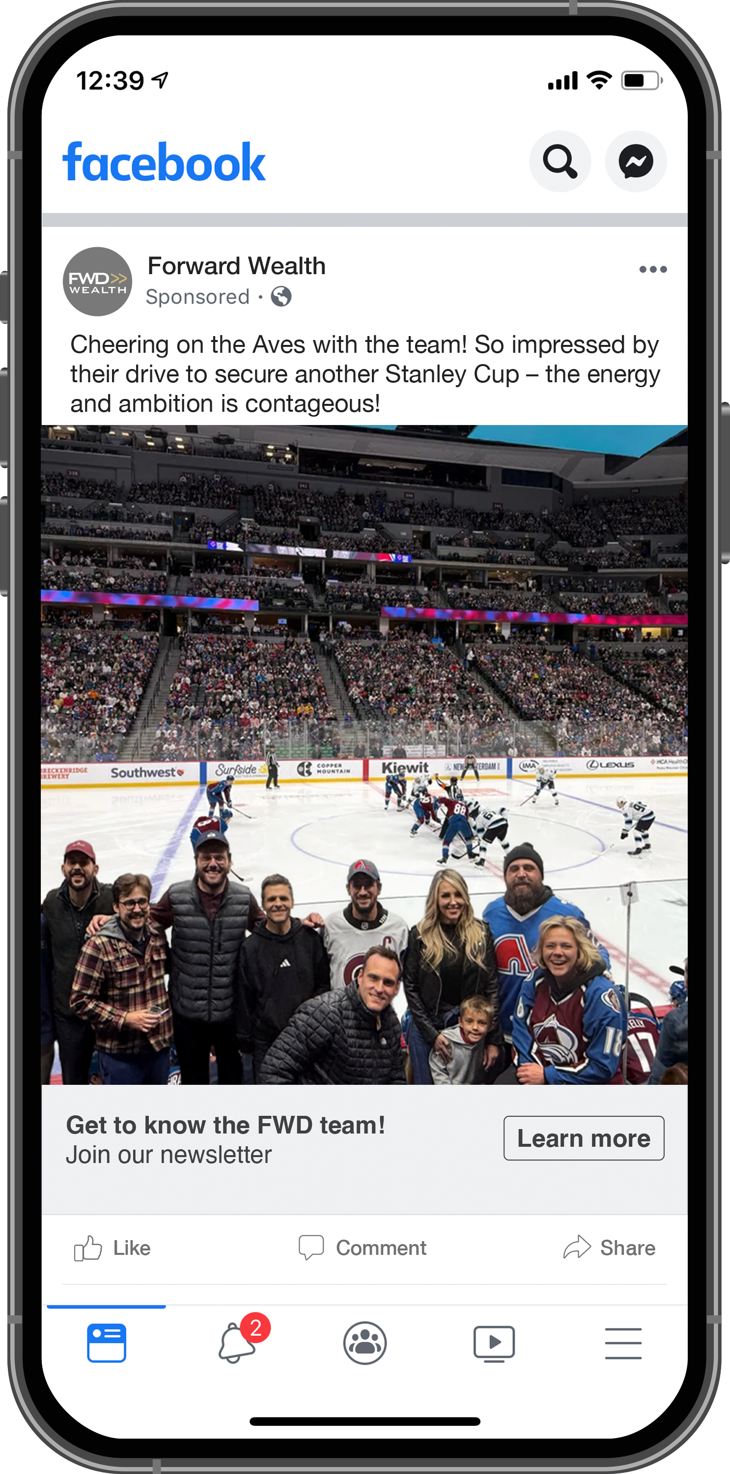 A group of people posing at an ice hockey game with players on the ice in the background.