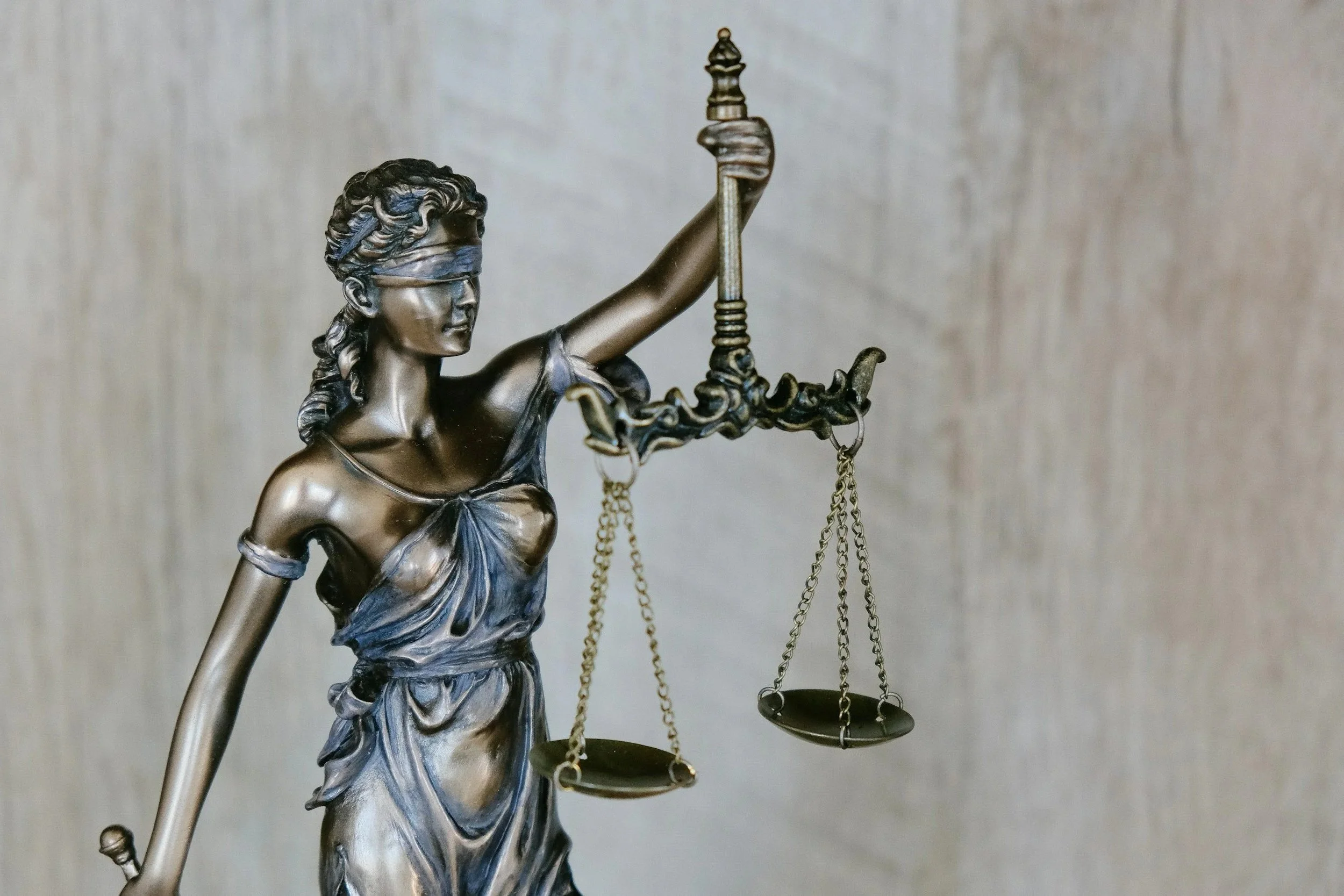 A statue of Lady Justice holding scales in her left hand and a sword in her right hand. She is wearing a blindfold over her eyes.