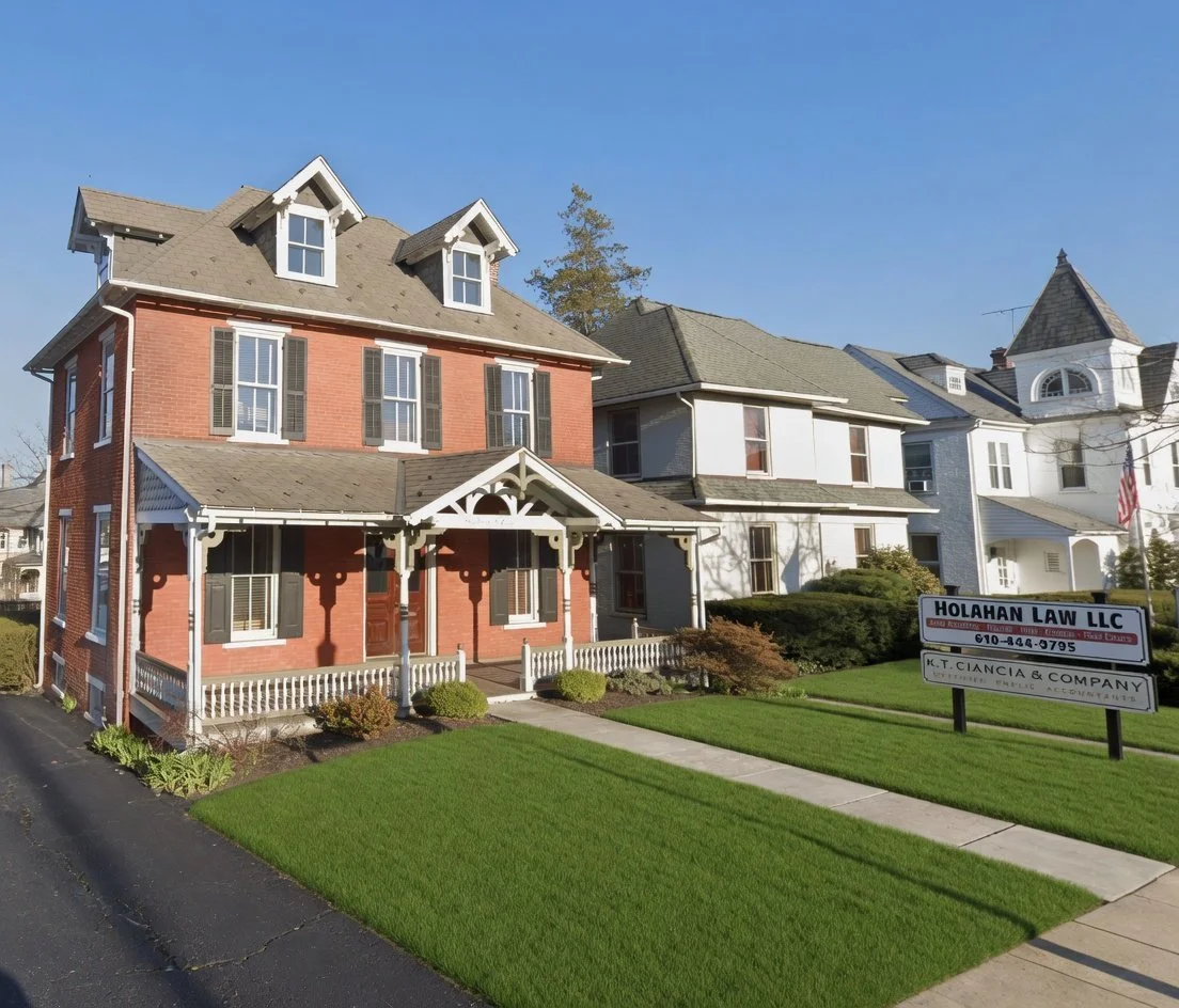 A row of three-story Victorian houses with manicured lawns and a business sign for law offices, under a clear blue sky.