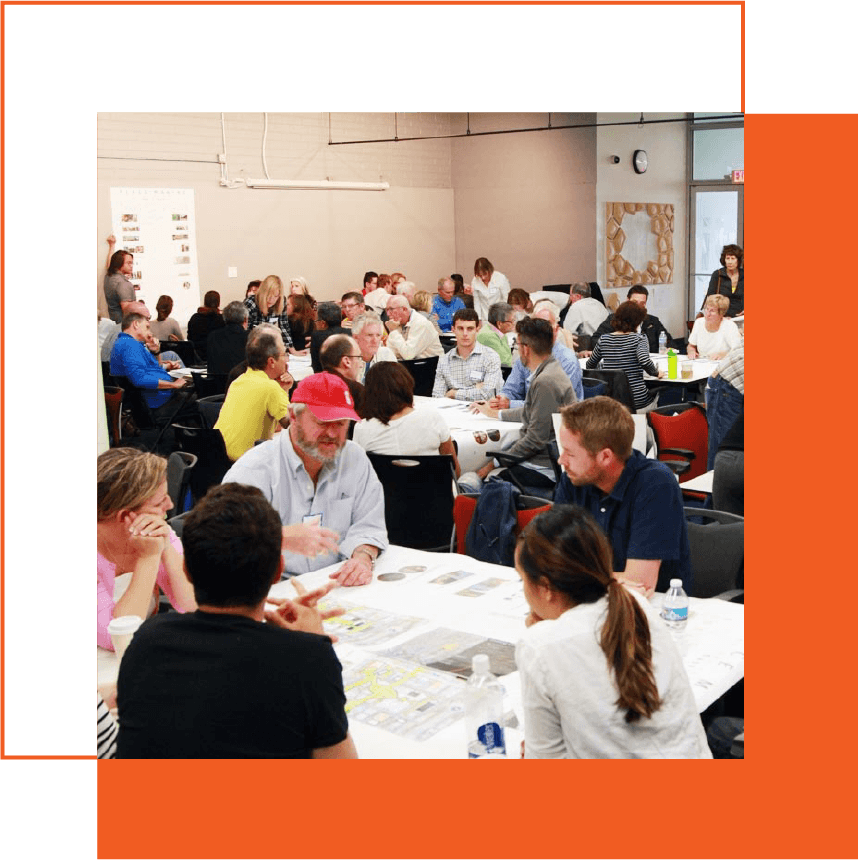 People sitting at tables in a large conference room, participating in a group event or workshop, with some individuals engaging in discussions and activities.