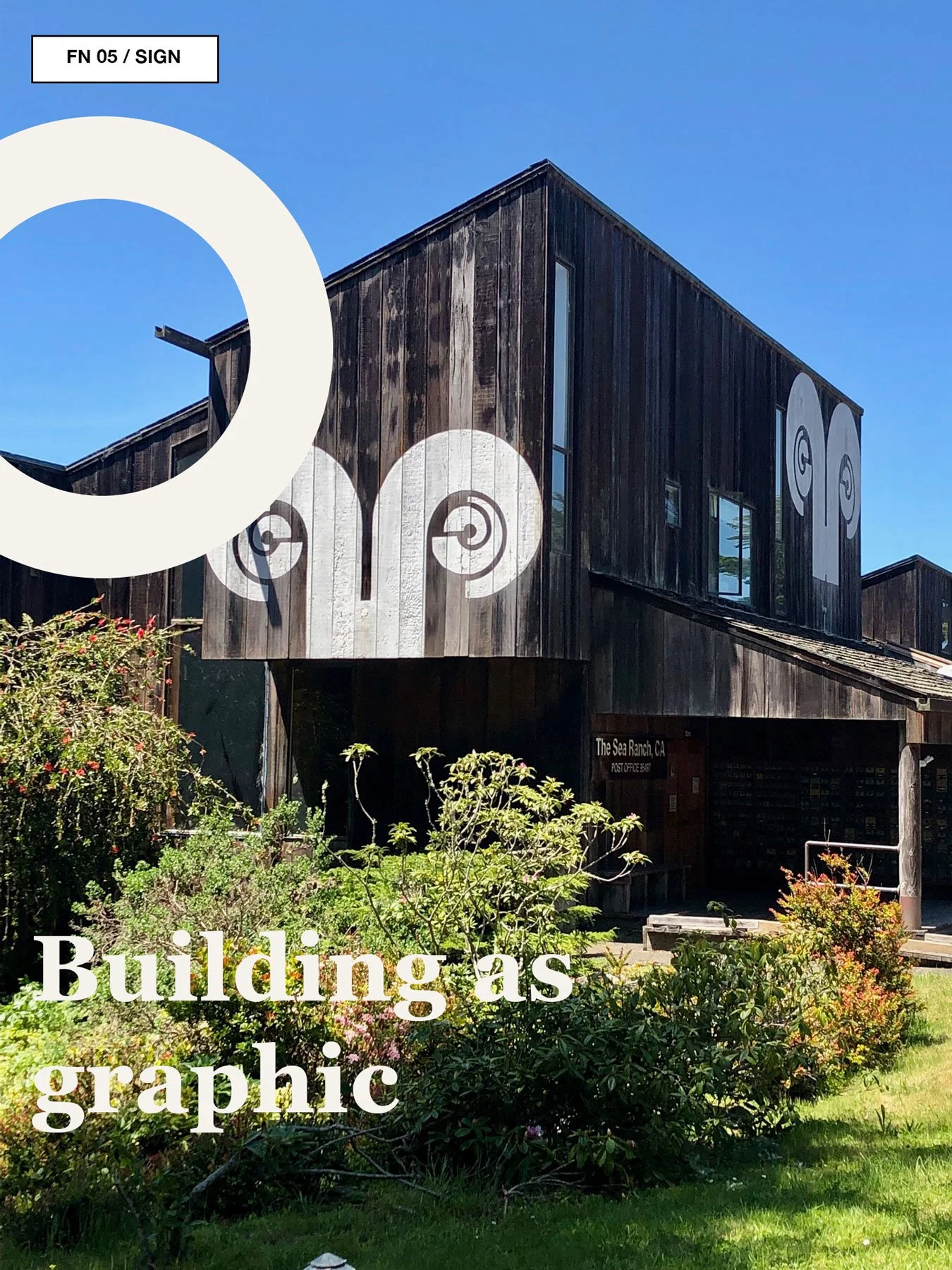 Weathered Sea Ranch building with bold white ram-like graphic painted on the exterior.