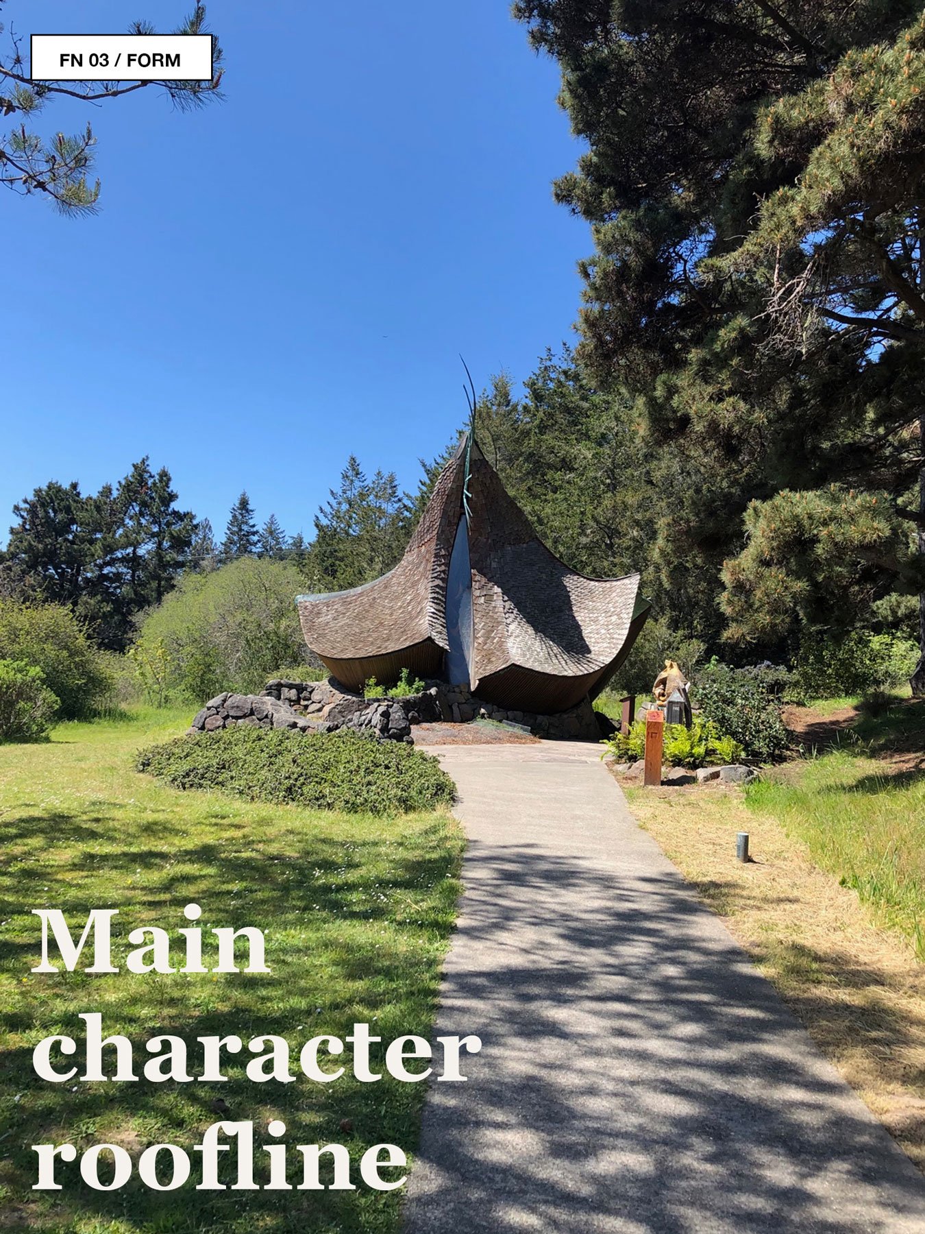 Sea Ranch chapel-like building with expressive shingled roof in a meadow.