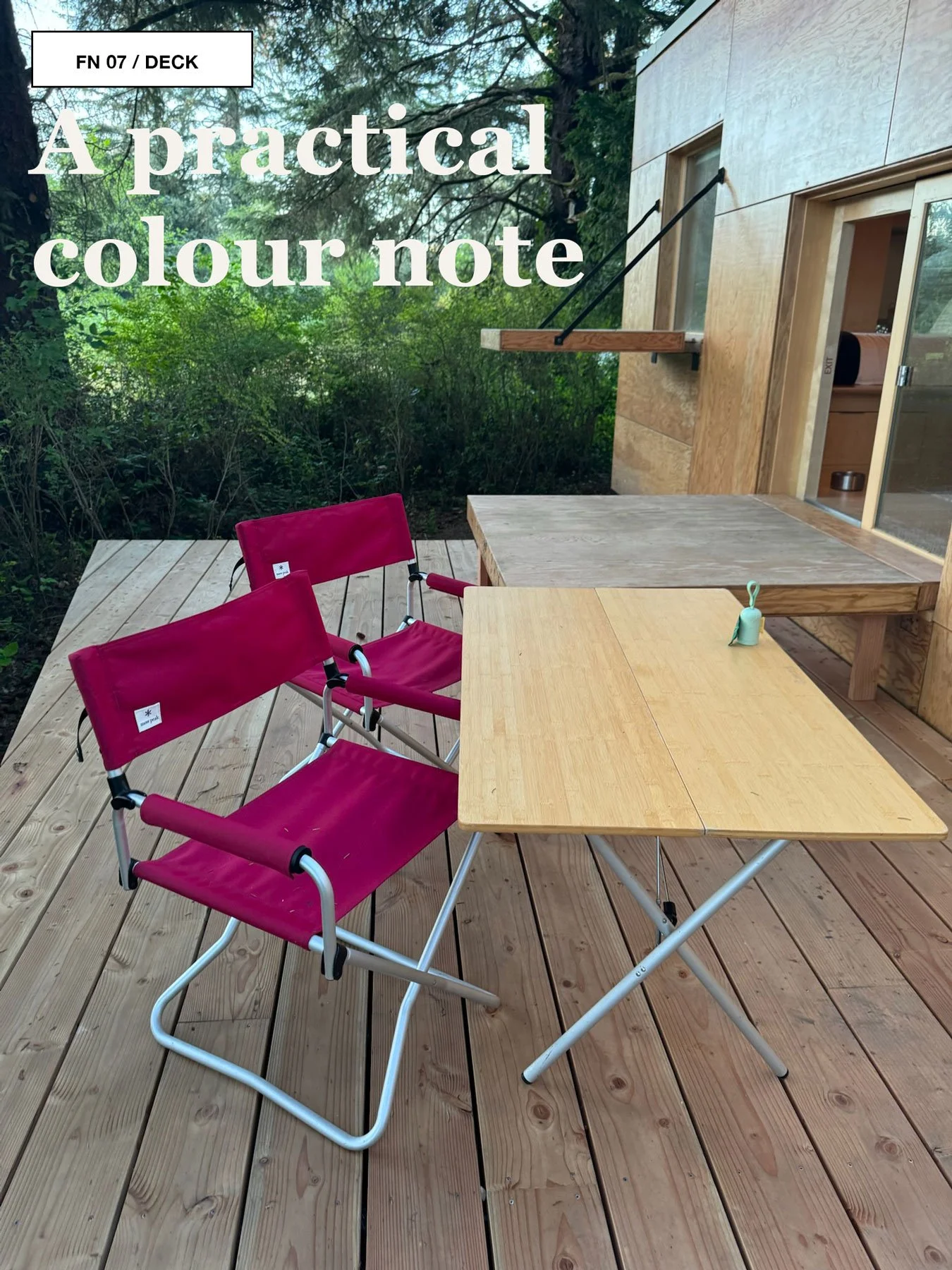 Red Snow Peak camp chairs and a folding table arranged on a timber deck outside a cabin.
