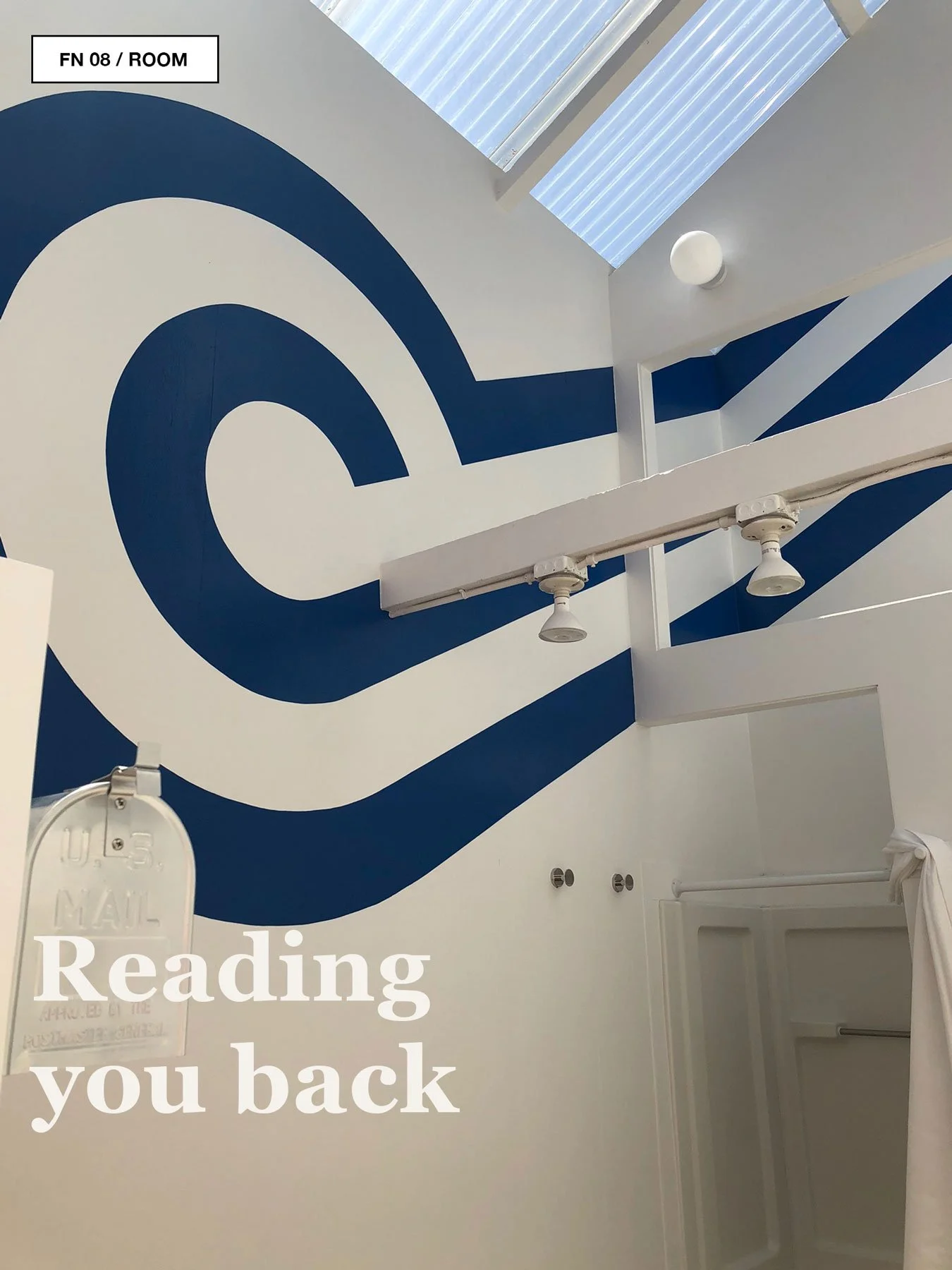 Blue circular and stripe supergraphic on a white Sea Ranch interior wall beneath skylights.