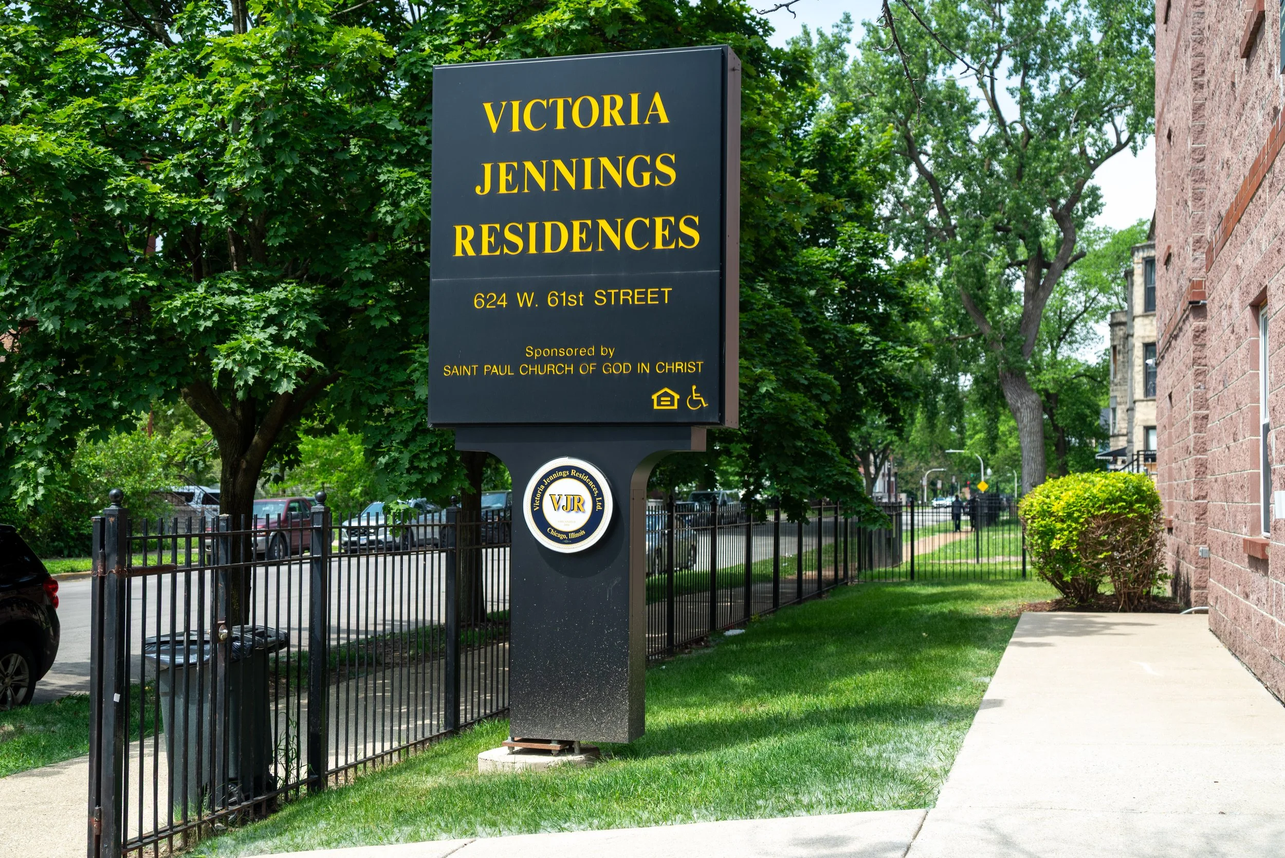Sign for Victoria Jennings Residences at 624 W. 61st Street, sponsored by Saint Paul Church of God in Christ, with icons indicating accessibility and housing.