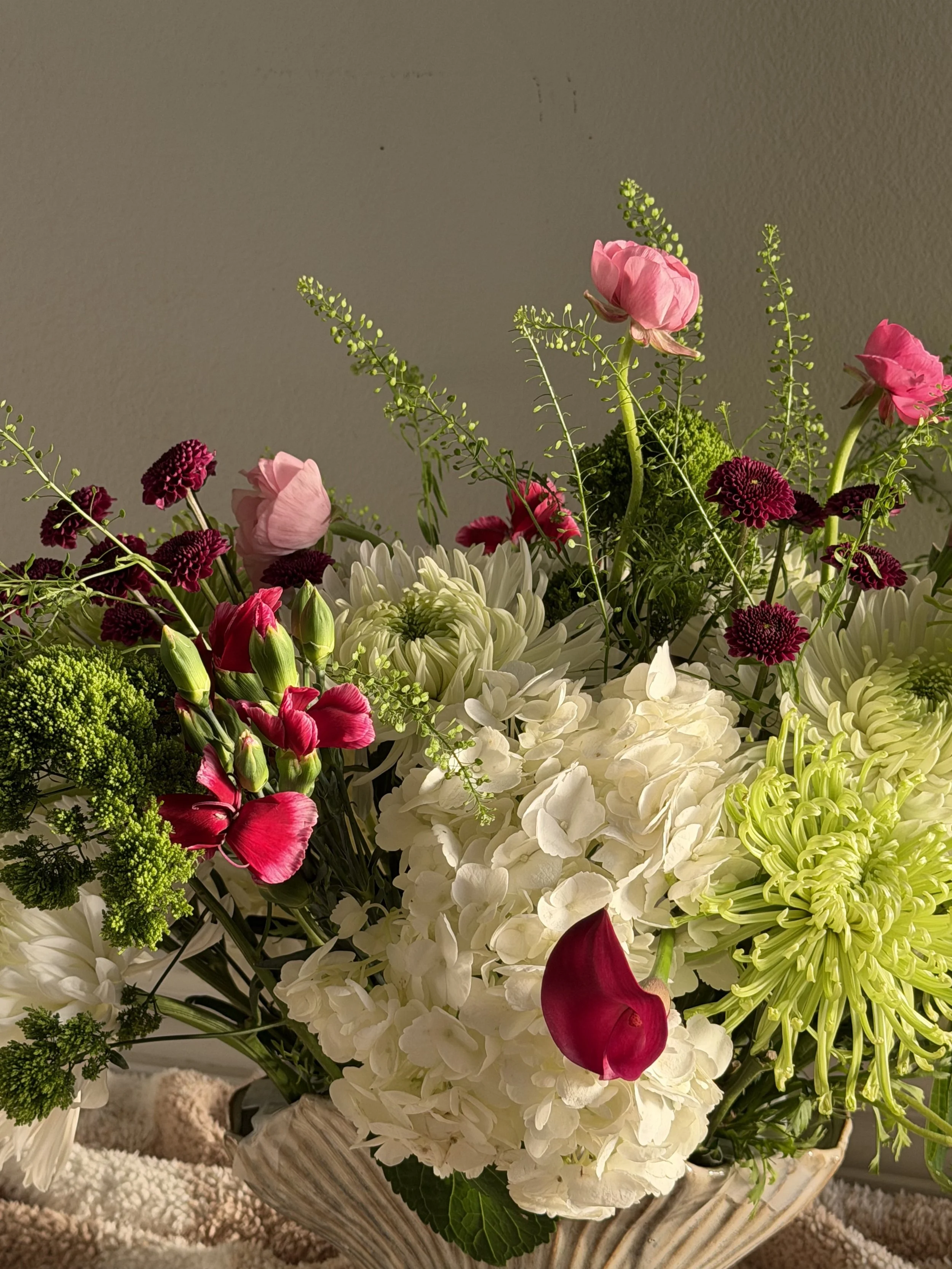 A floral arrangement with pink, purple, green, and white flowers in a decorative bowl.