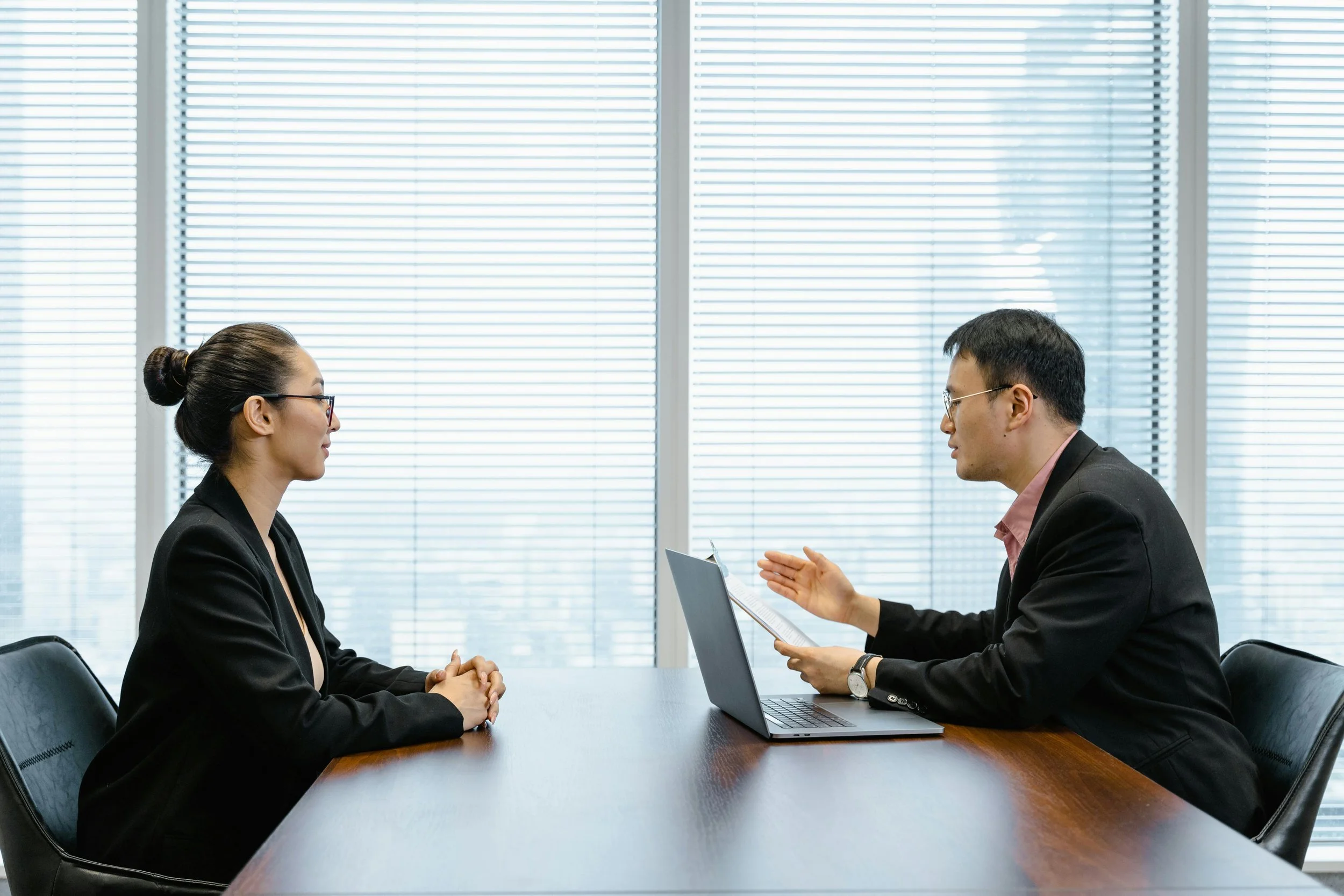 Two professionals in a structured one-on-one meeting across a desk, representing behavioural hiring consultation and candidate assessment - The WELLPLACED Method - Recruitment Sydney