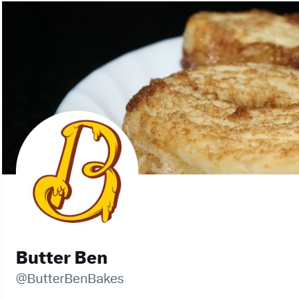 Close-up of two banana pancakes on a white plate, with a logo of a yellow letter B with a hand holding a fork. The background is black.