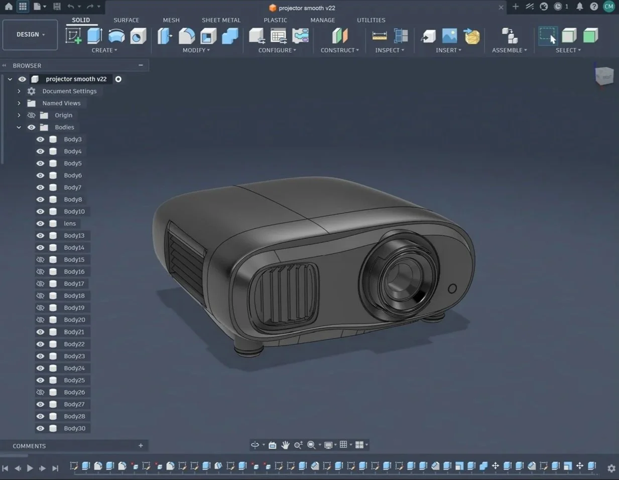 A 3D CAD model of a projector designed in a CAD software interface. The model is black and features a large lens in the front, with vents on the sides. The software interface shows various modeling tools and a project tree on the left.