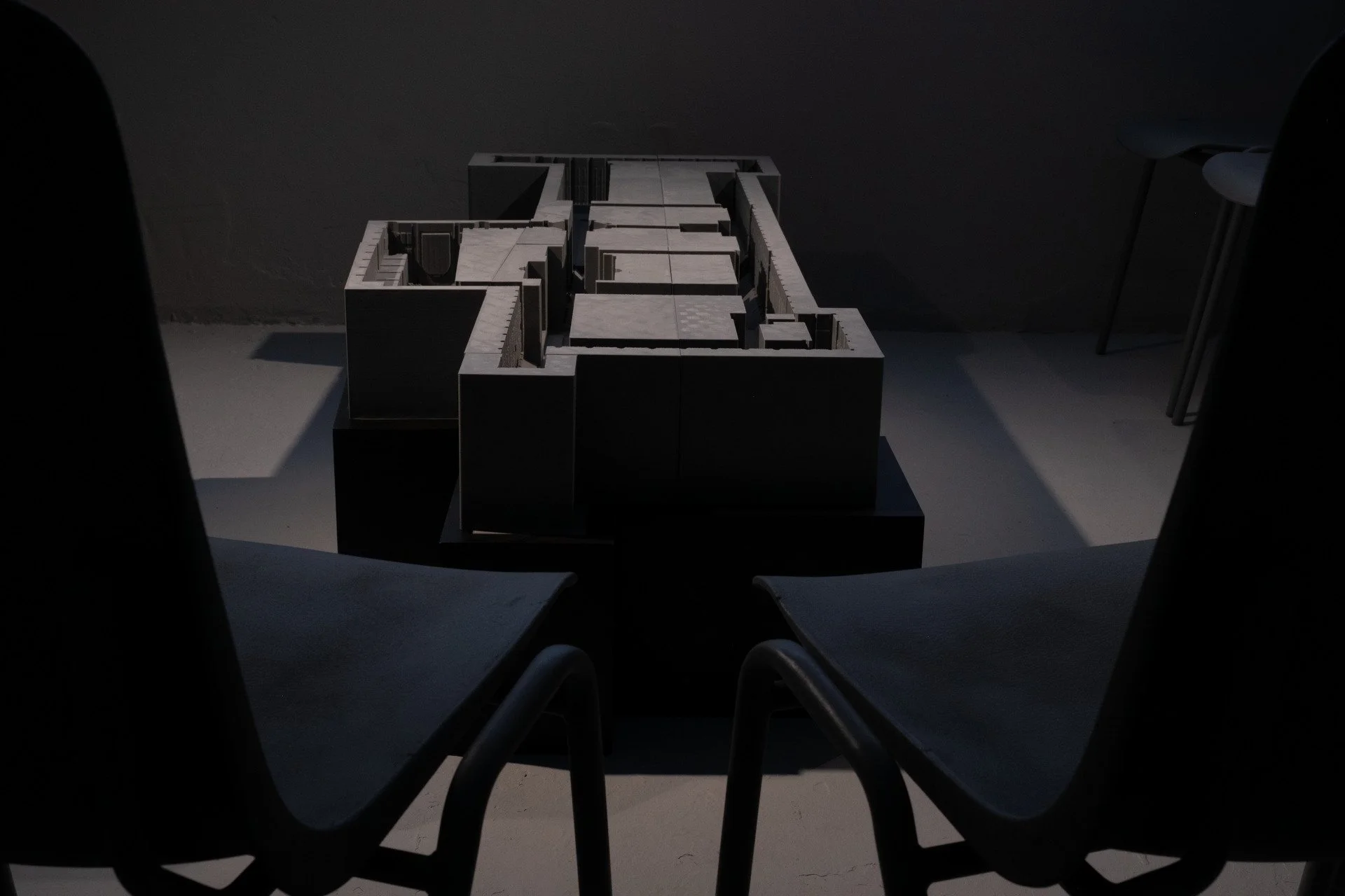 A sculpture or model of a building or structure placed on a table, viewed from the perspective of someone sitting in front of it in a dimly lit room.
