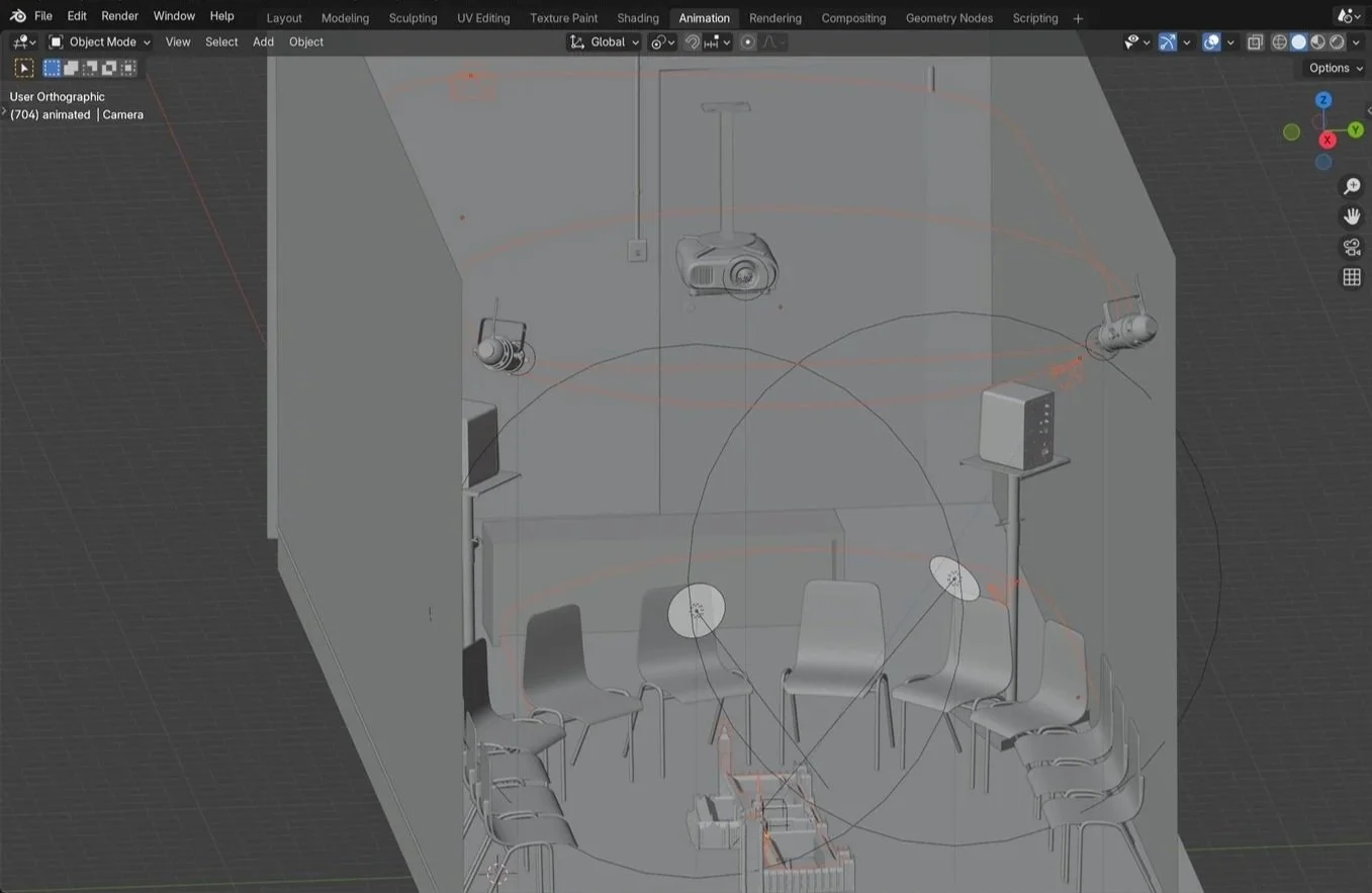 A 3D modeling workspace showing a room with chairs arranged in a circle, lighting equipment, and other devices, likely used for virtual meetings or presentations.