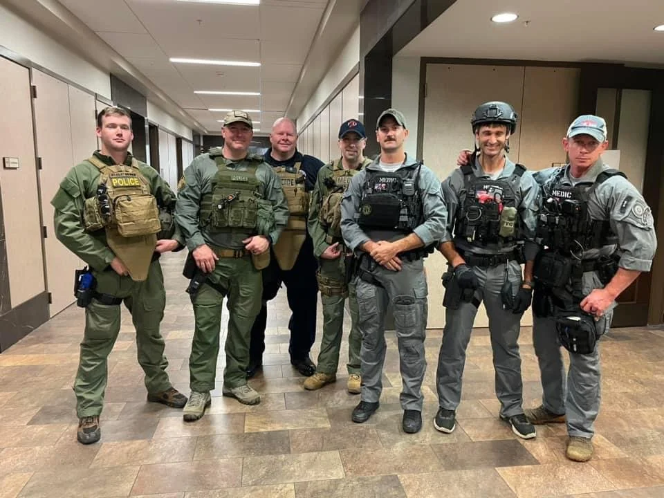 The Founder of Noah's Hammer and a group of other law enforcement officers in tactical gear standing in a hallway.