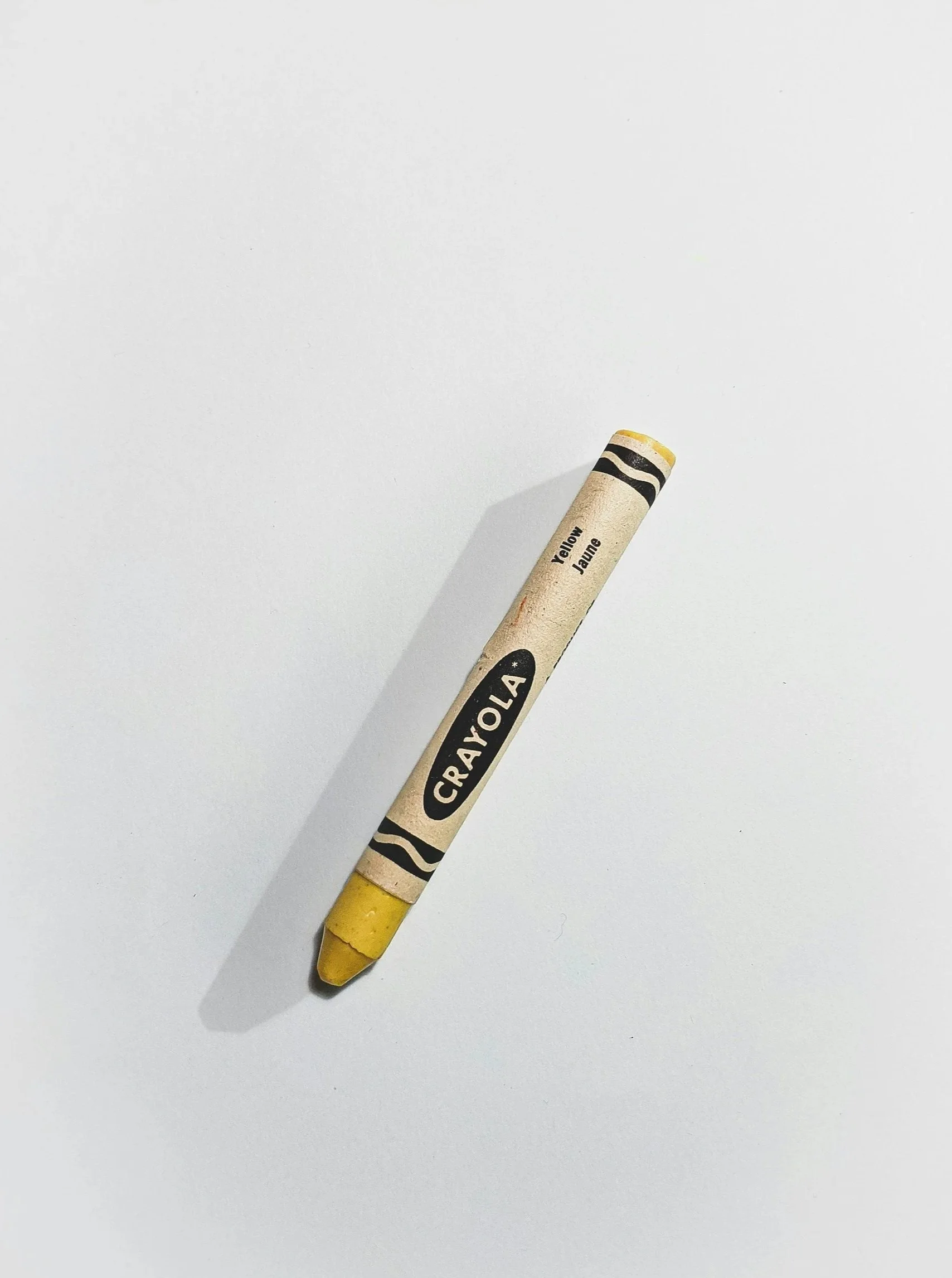Gelber Wachsmalstift auf weißem Hintergrund, mit der Aufschrift 'Yellow' und 'Jaune'