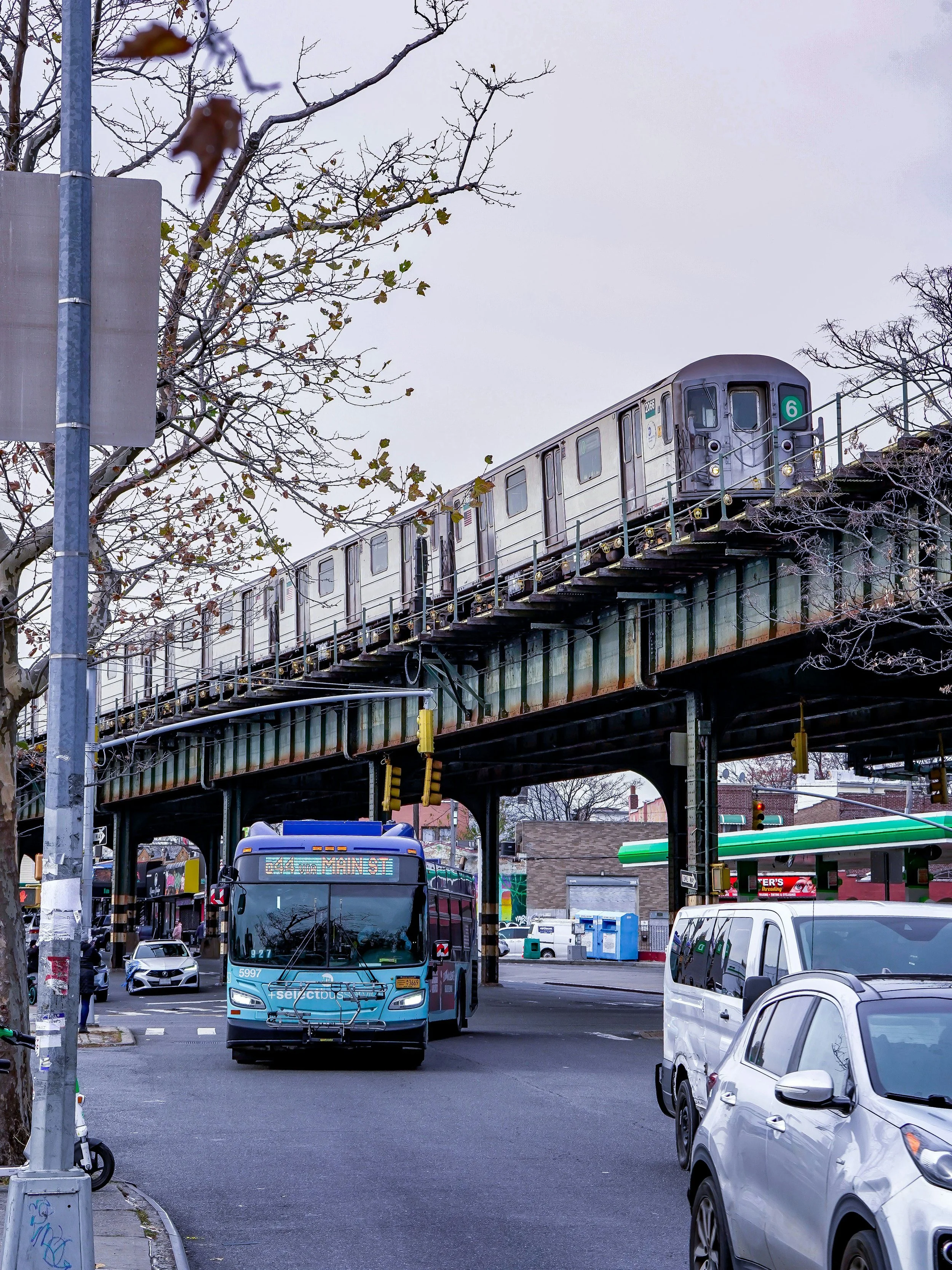 Elevated 6 train passes over street with bus and cars in Parkchester, The Bronx, NY