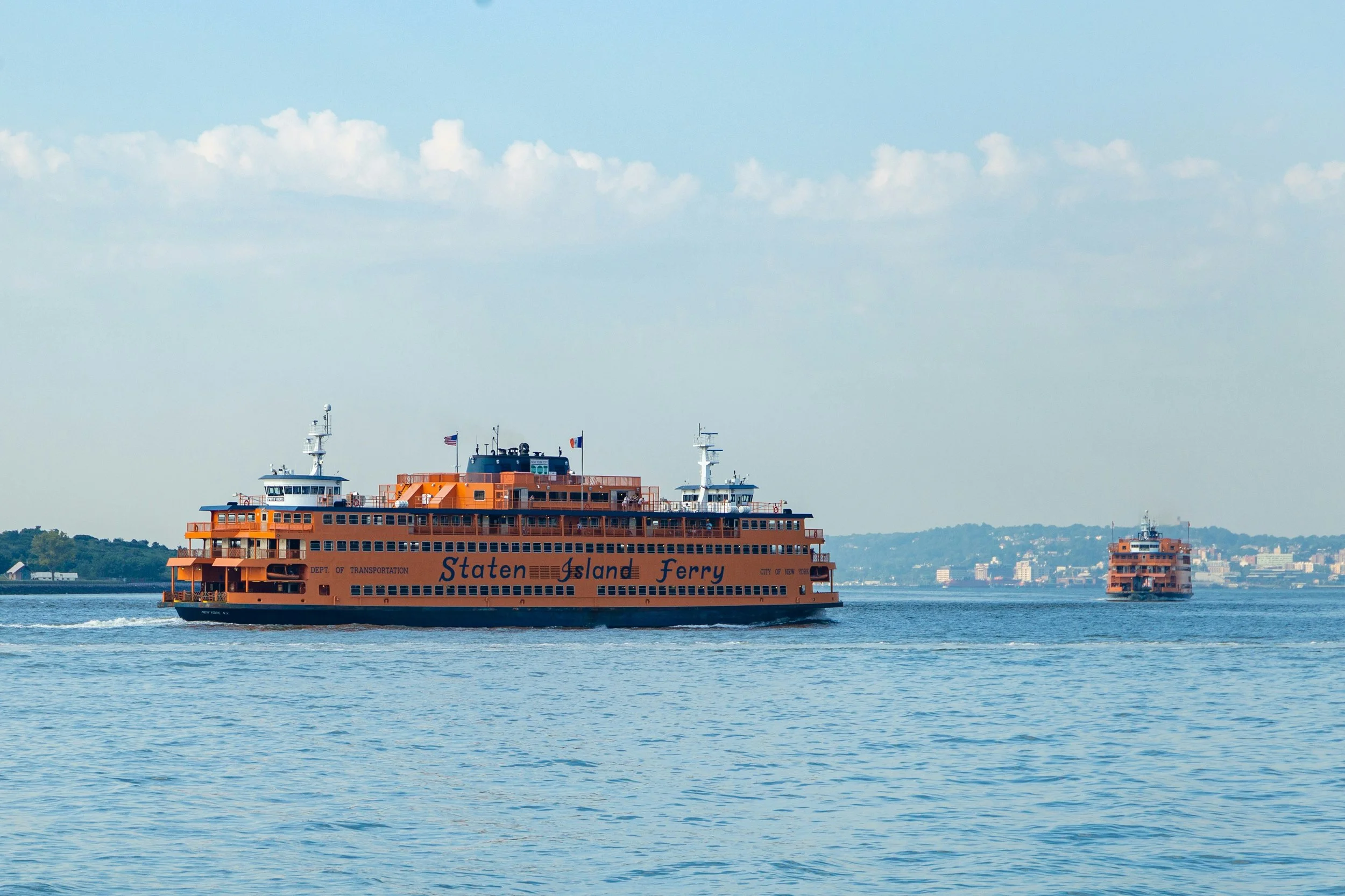 Two orange staten island ferries on the water
