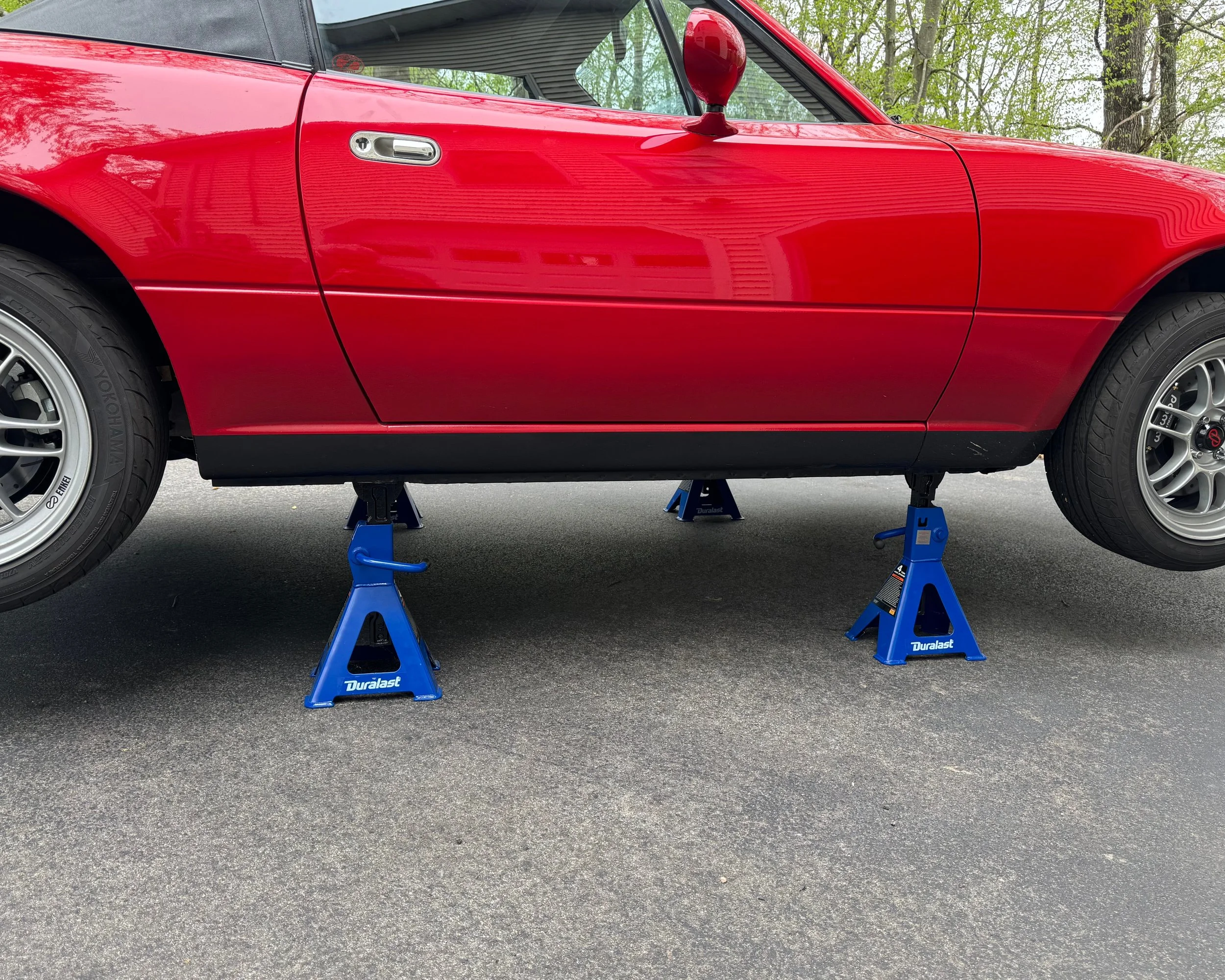 NA Mazda Miata MX-5 classic red on two jack stands in driveway