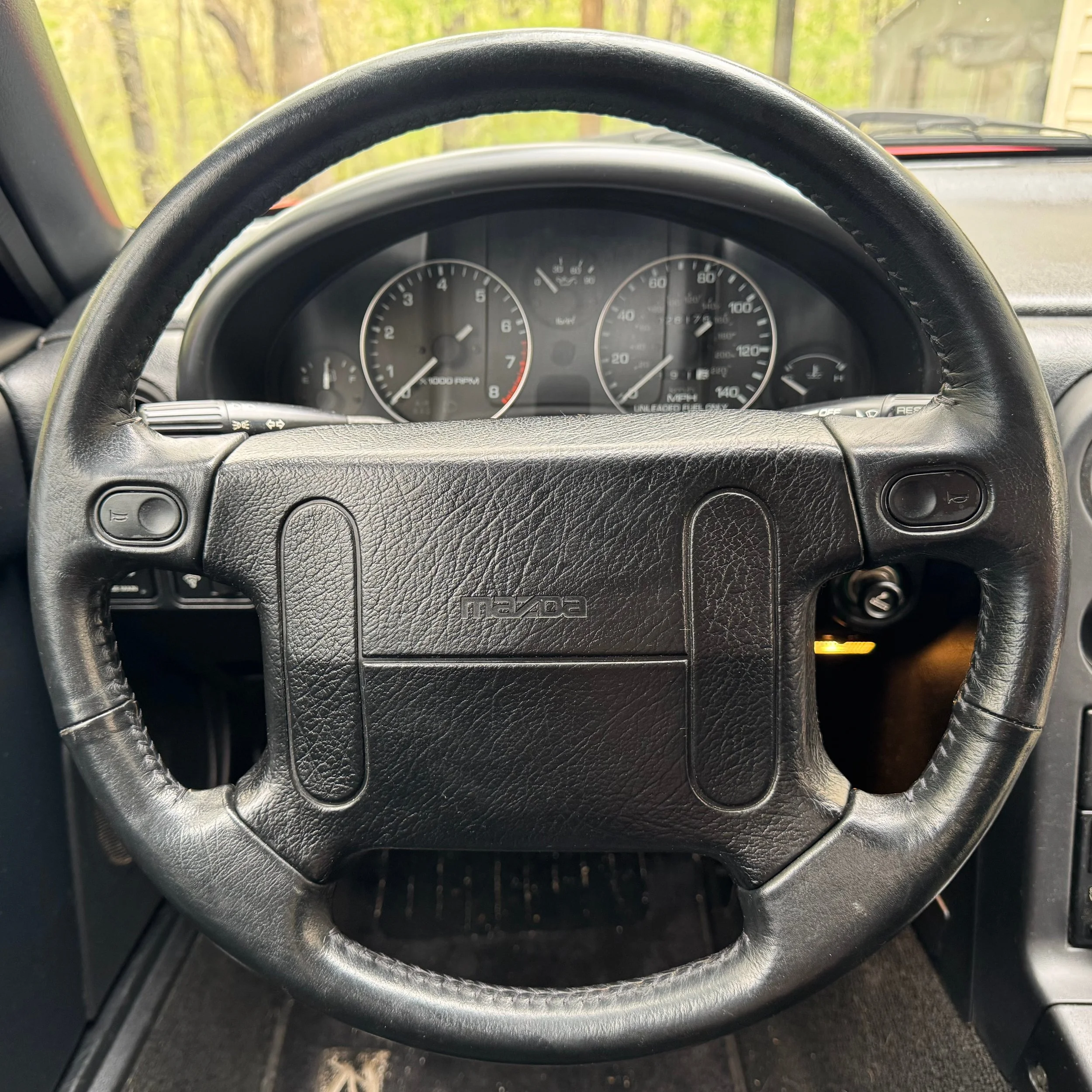 Steering wheel and gauges for a 1990 classic red Mazda Miata MX-5.