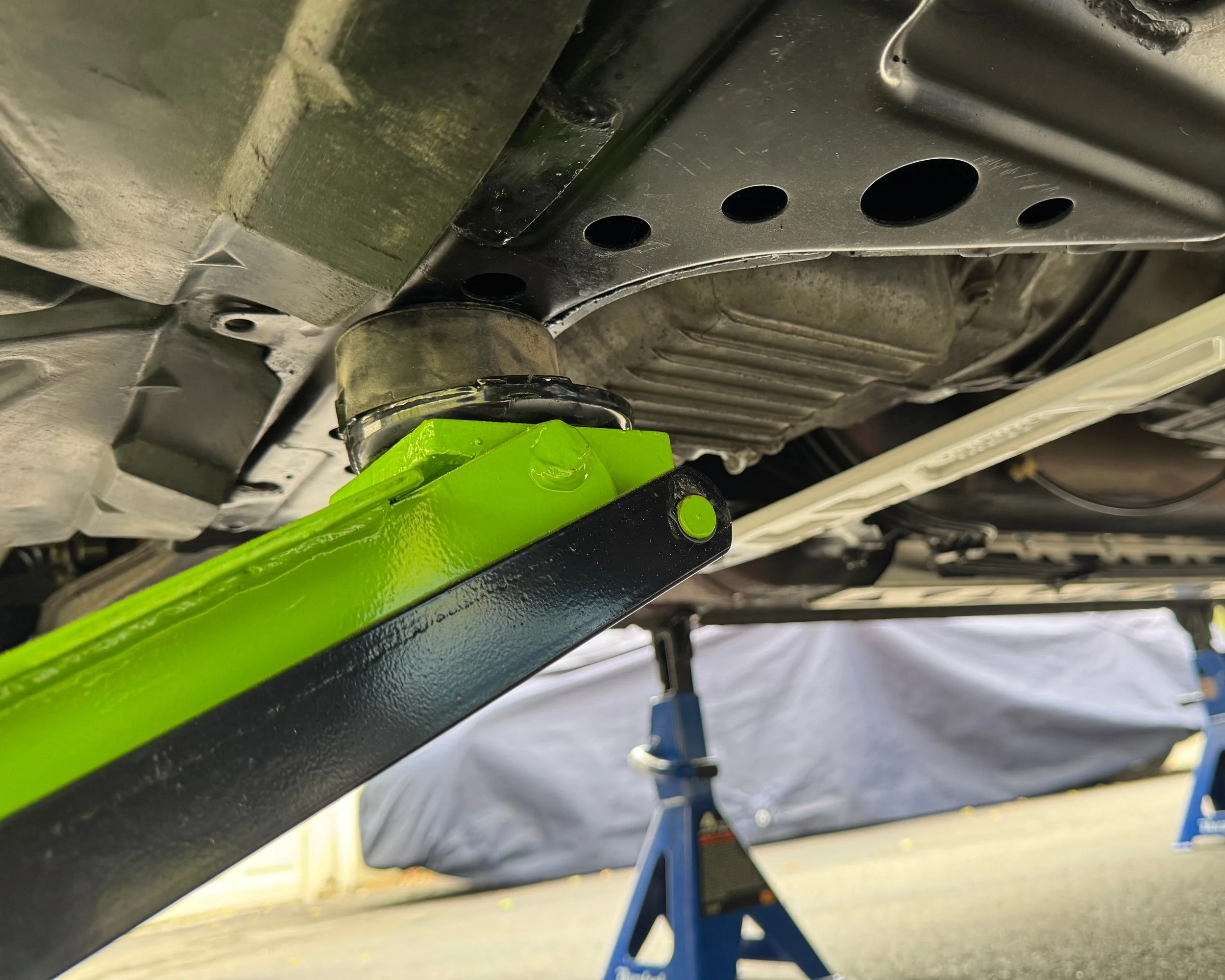 NA Mazda Miata MX-5 hydraulic lift under the front metal crossmember.  Image shows where to place the hydraulic jack.