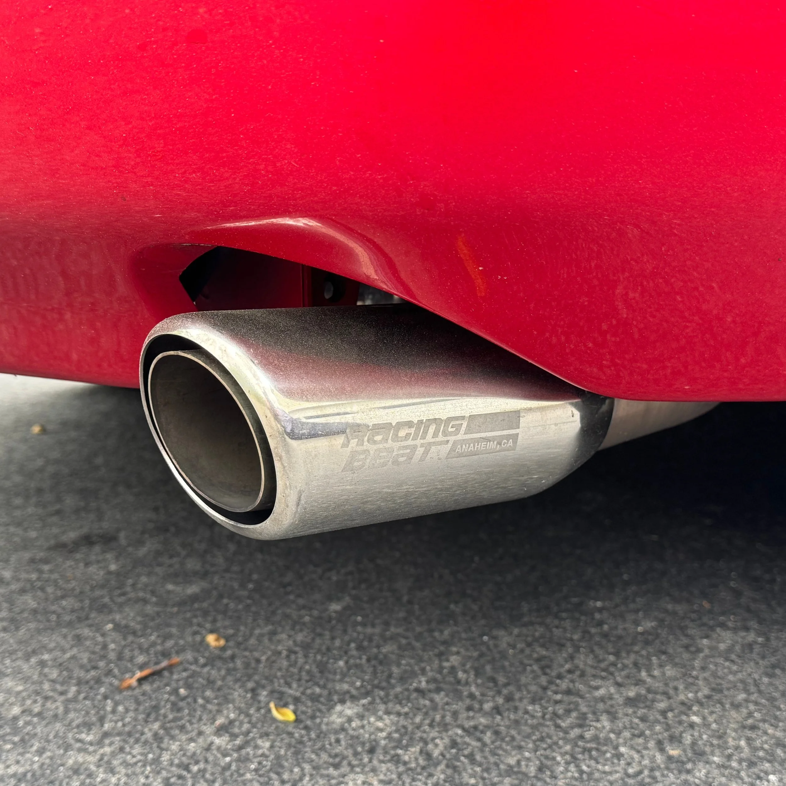 Racing beat exhaust and rear bumper for a 1990 classic red Mazda Miata MX-5.