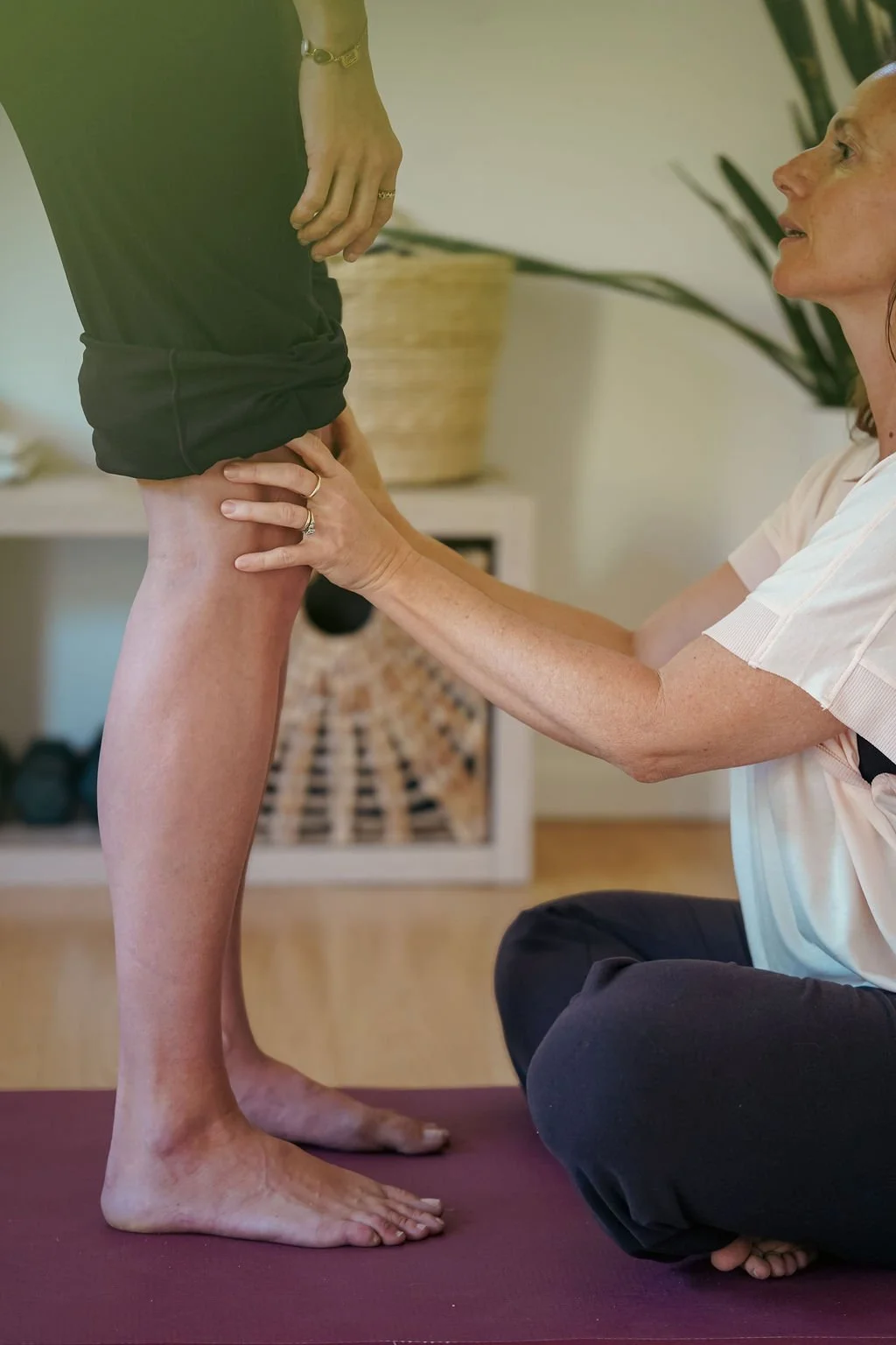 Barbara Stamis Somatic Bodywork and Breathwork Practitioner, sitting on the floor kneeling and holding a person's thigh during a bodywork session in her studio at Topanga, Canyon