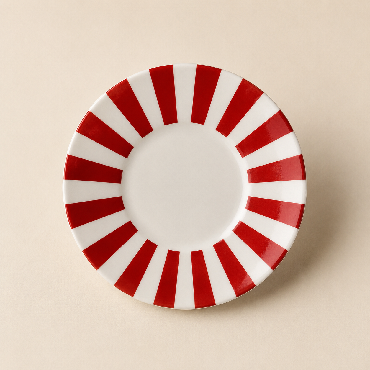 A round white plate with red and white stripes around the edge, viewed from above on a beige background.