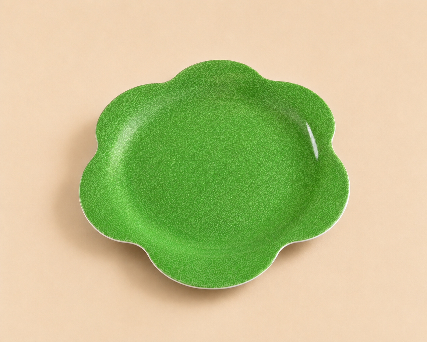 A green, flower-shaped ceramic bowl with a textured surface, placed on a beige background.