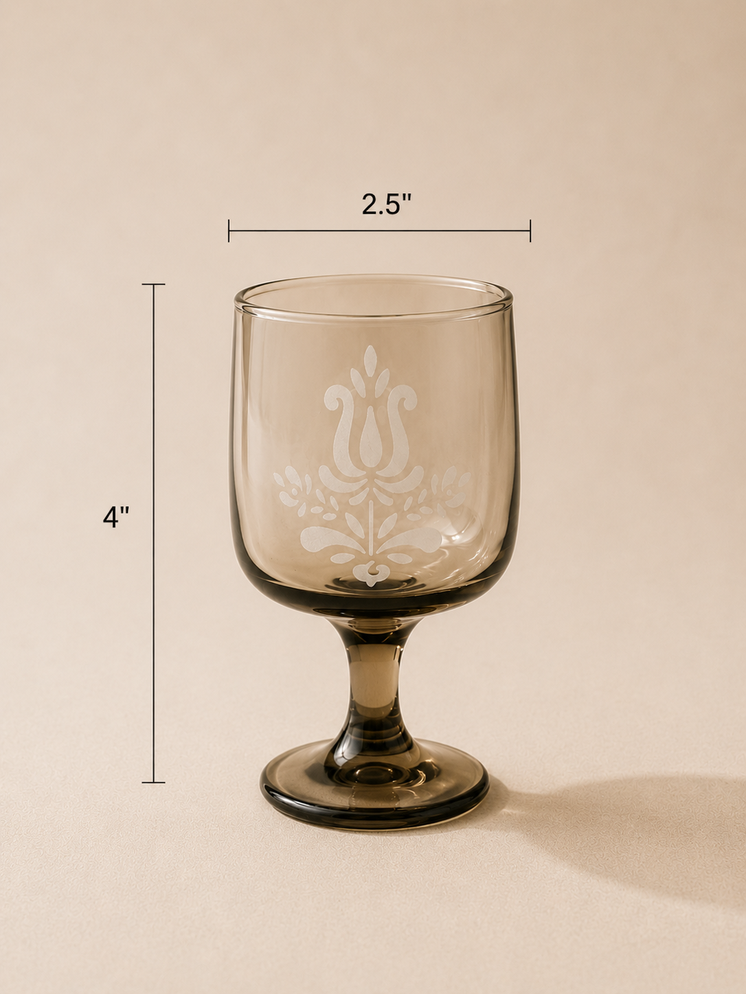 A clear wine glass with engraved floral design, 4 inches tall and 2.5 inches wide, placed on a neutral background.