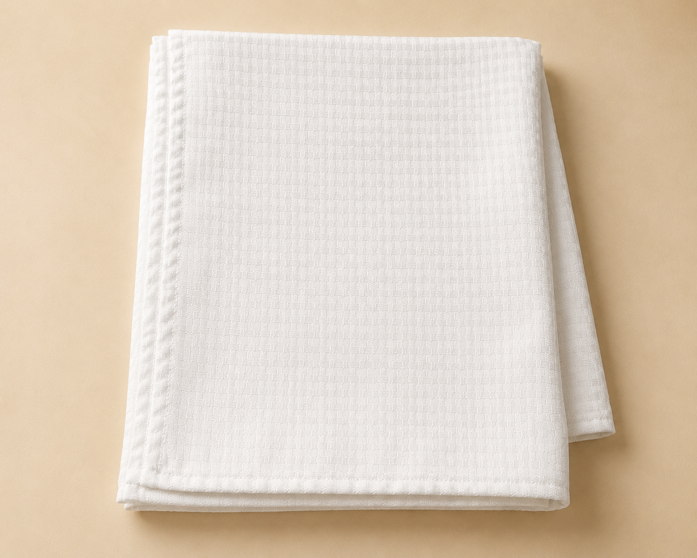A folded white textured towel on a beige surface.