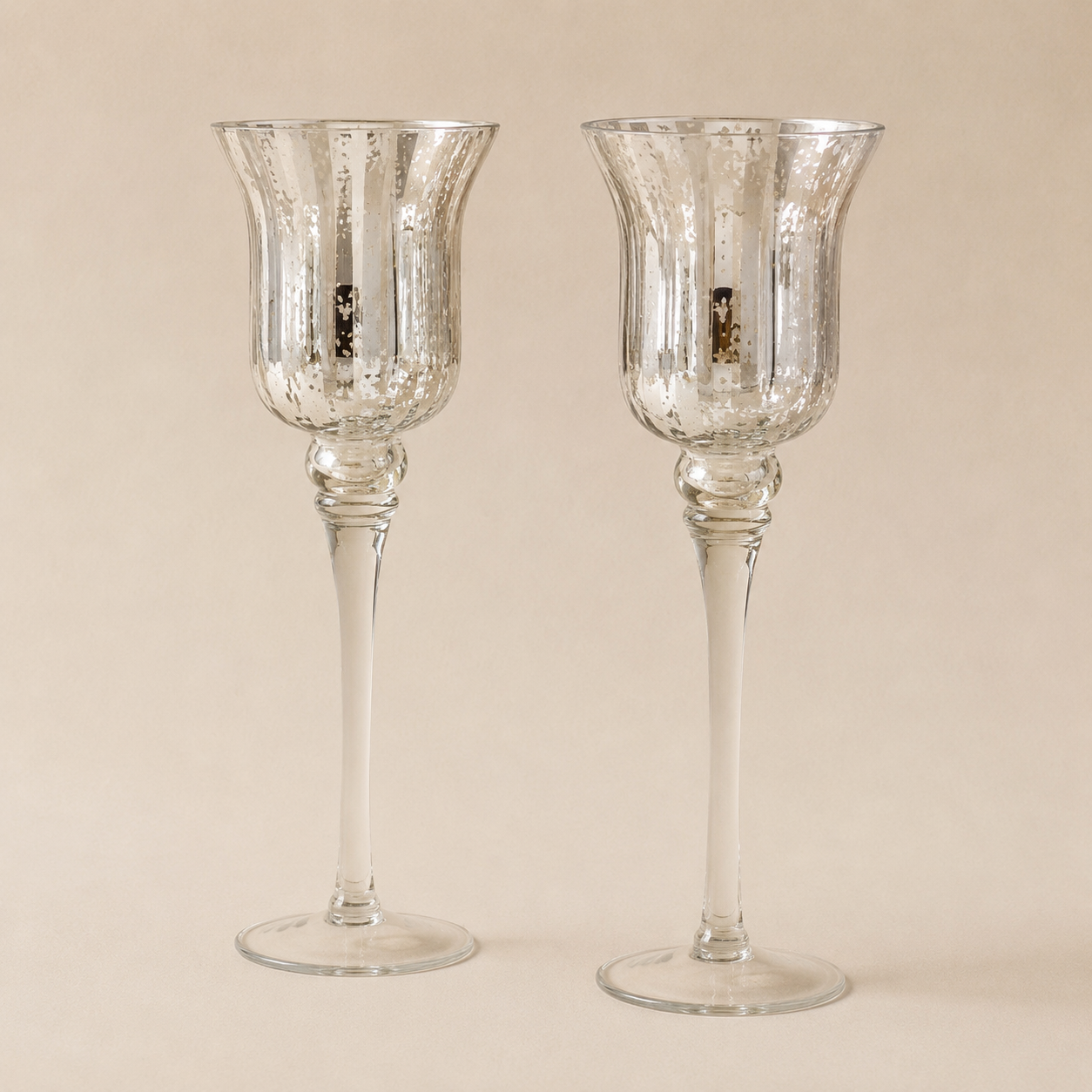 Two silver candle holders with a tall, elegant design and a reflective surface against a plain background.