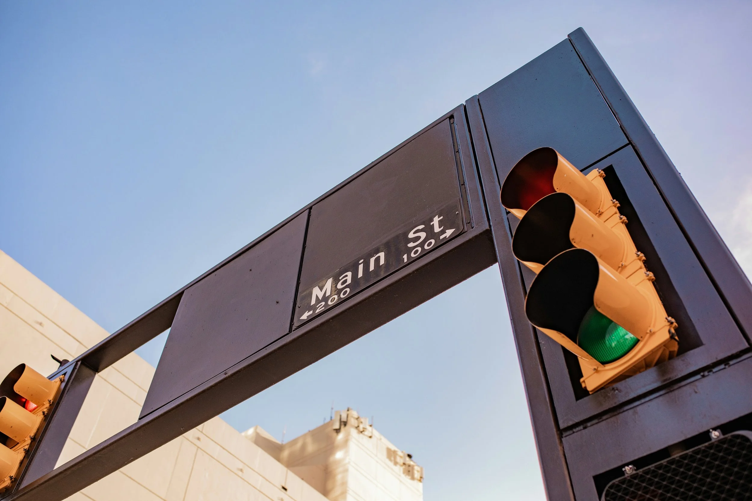 Traffic light at an intersection with a street sign reading 'Main St'. Clear blue sky in the background.