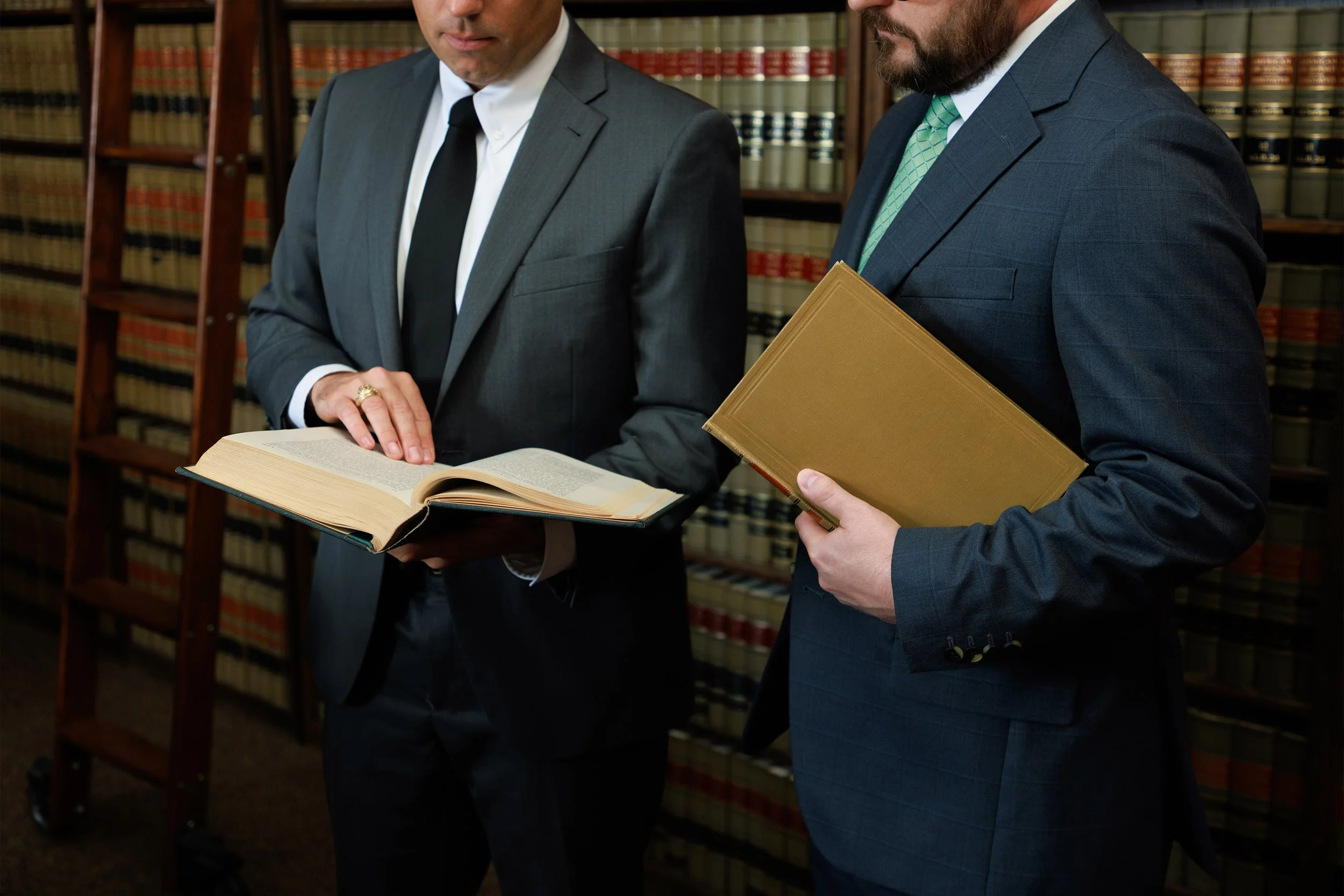 Two men in suits examining legal books in a law library.