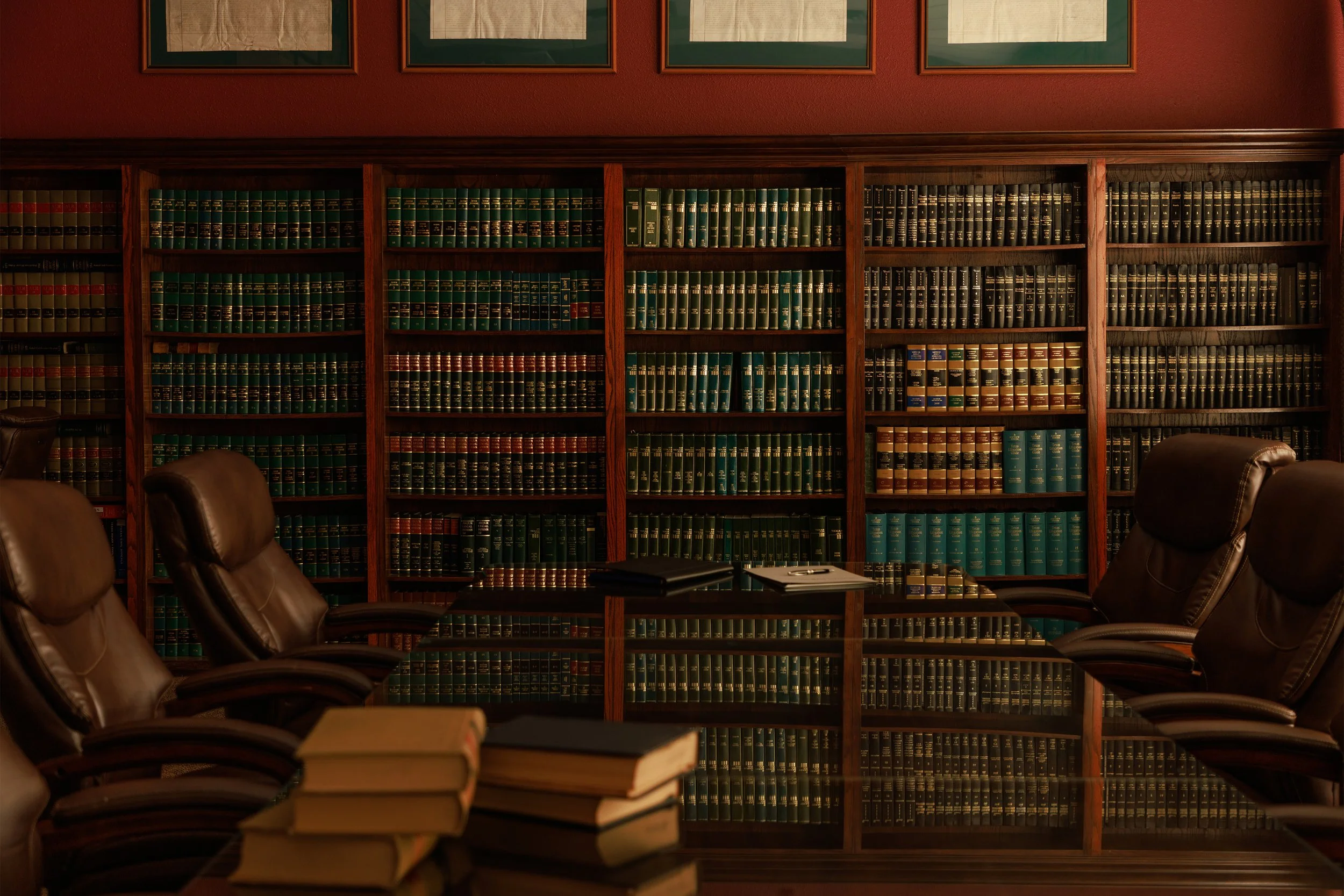 A bookshelf filled with legal books in a law office or library with chairs and papers in the foreground.