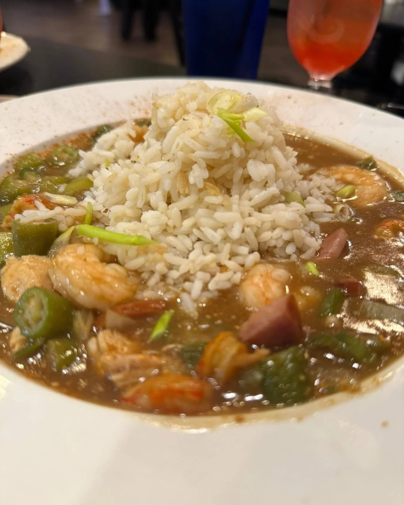 A bowl of rice served with a shrimp and vegetable stew.