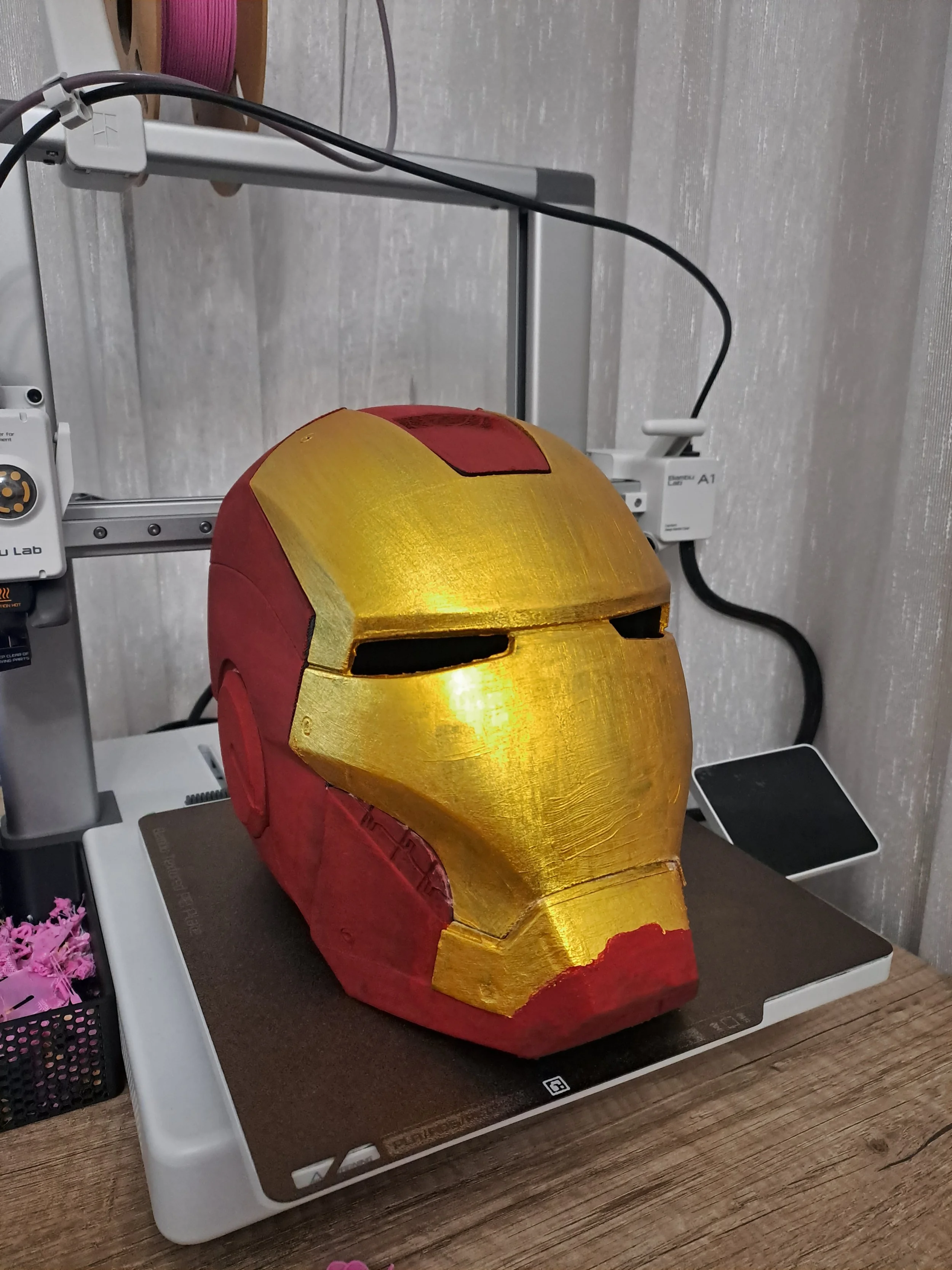 A red and gold Iron Man helmet replica placed on a lab table next to laboratory equipment.