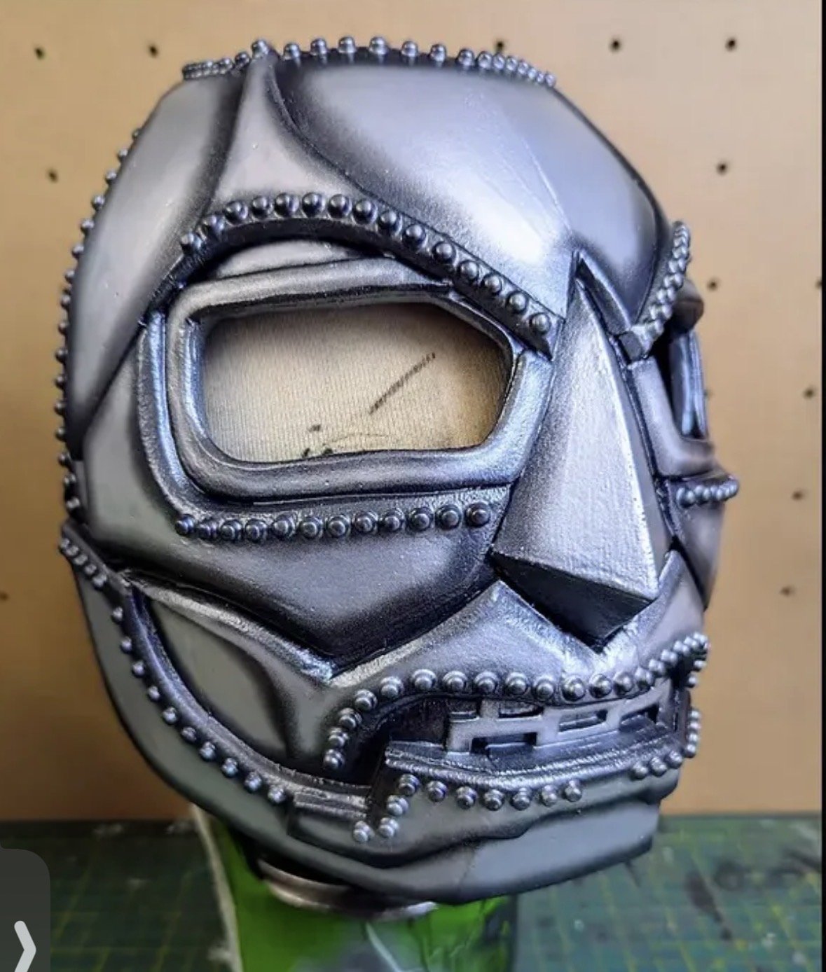 A custom-made foam mask resembling a superhero or comic book character, decorated with metal studs and geometric shapes.