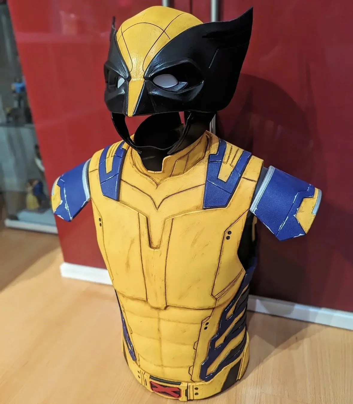 Bust of a character wearing a yellow and blue armored costume with a black and yellow helmet resembling a comic book superhero.