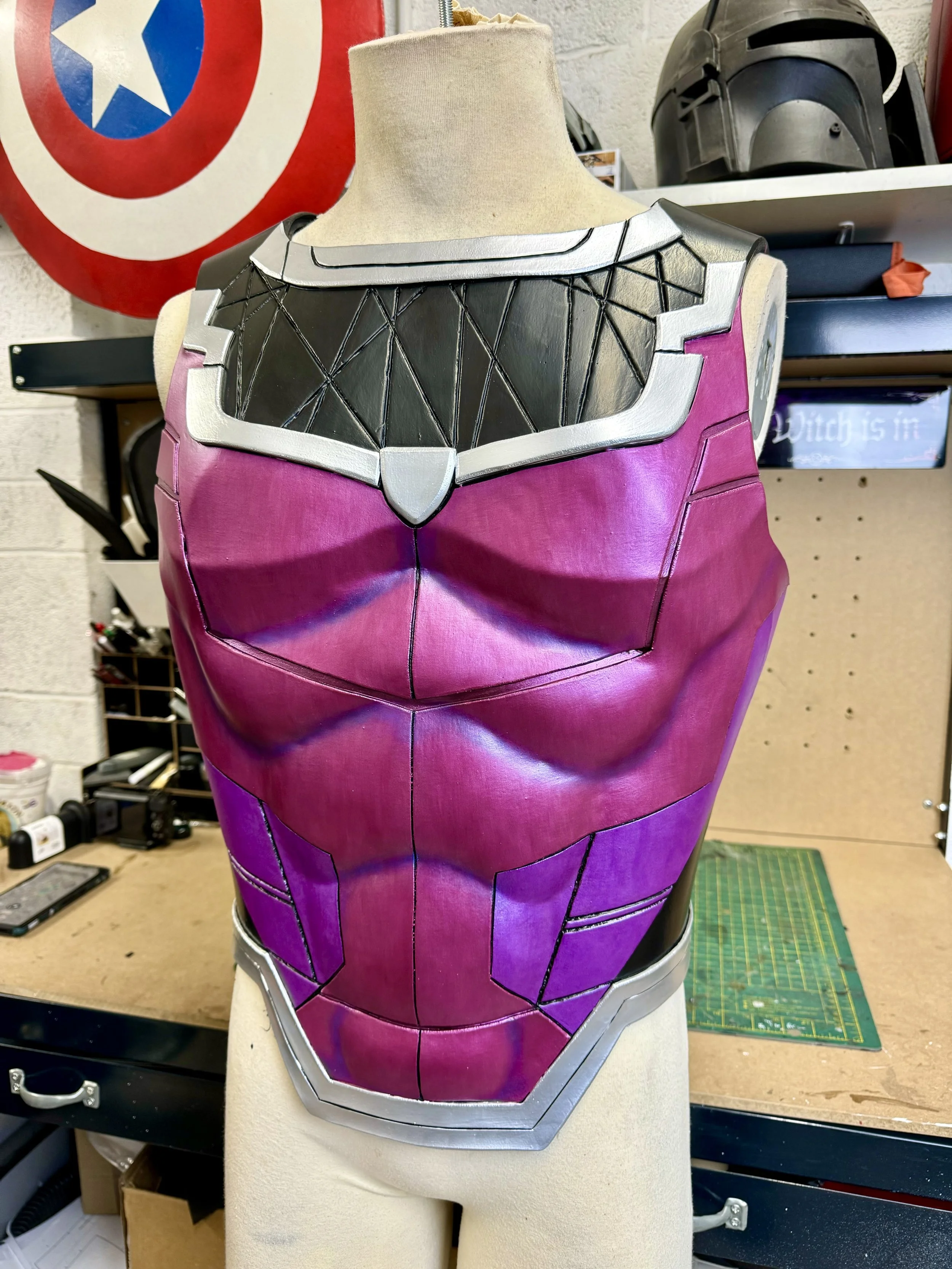 A costume piece resembling the upper torso of Gambit, with metallic silver, black, and purple sections, displayed on a mannequin in a workshop setting.