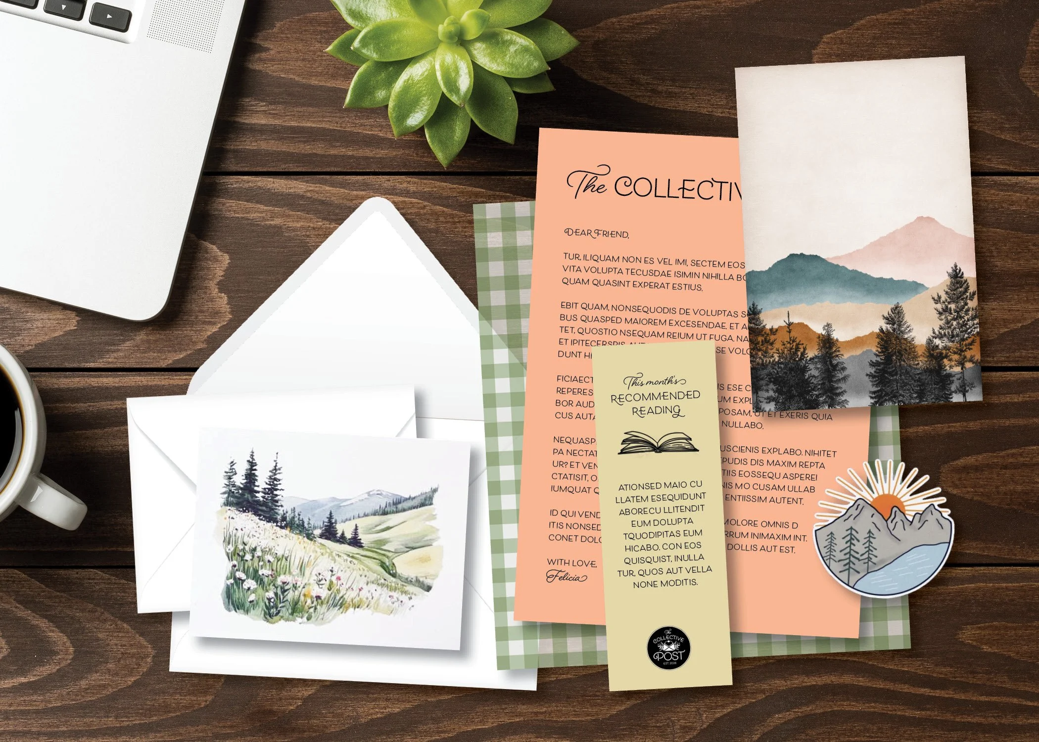 A flat lay of various stationery items on a wooden surface, including a small potted green succulent plant, a silver laptop keyboard, a white envelope with an illustration, colorful paper notes with printed text, a landscape painting, and a sticker of mountains and a lake.