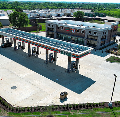 An aerial view of a 7-Eleven convenience store with a solar panel canopy covering the fuel pumps.