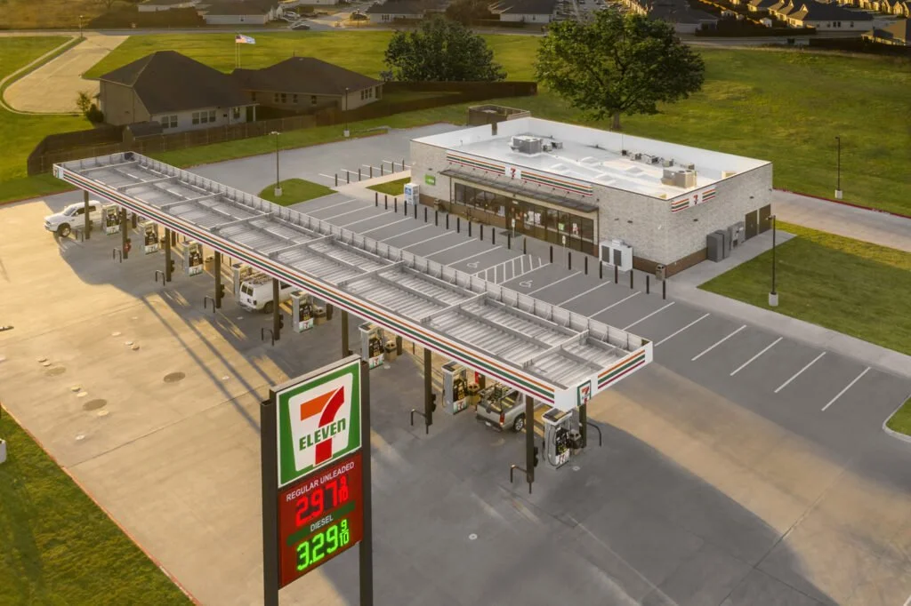 An aerial view of a 7-Eleven convenience store with a gas station, fueling pumps, and a parking lot.