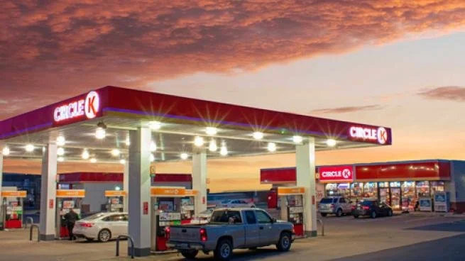 Circle K gas station at sunset with several cars parked at fuel pumps and in the store parking lot.
