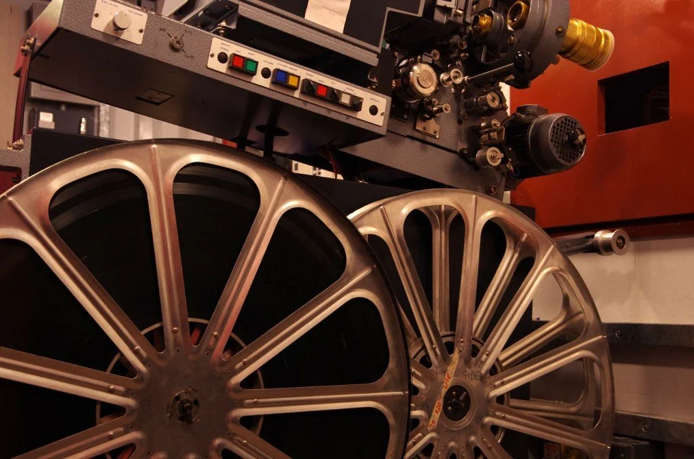 Two large, metallic suspension wheels manufactured for a vehicle, positioned in front of a precision machine used for their fabrication or inspection.