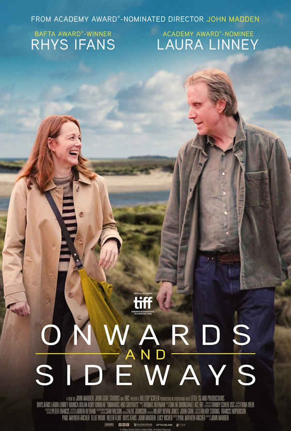 A women and a man walking outdoors in casual clothing, smiling and looking at each other against a landscape of grass and water with a partly cloudy sky.